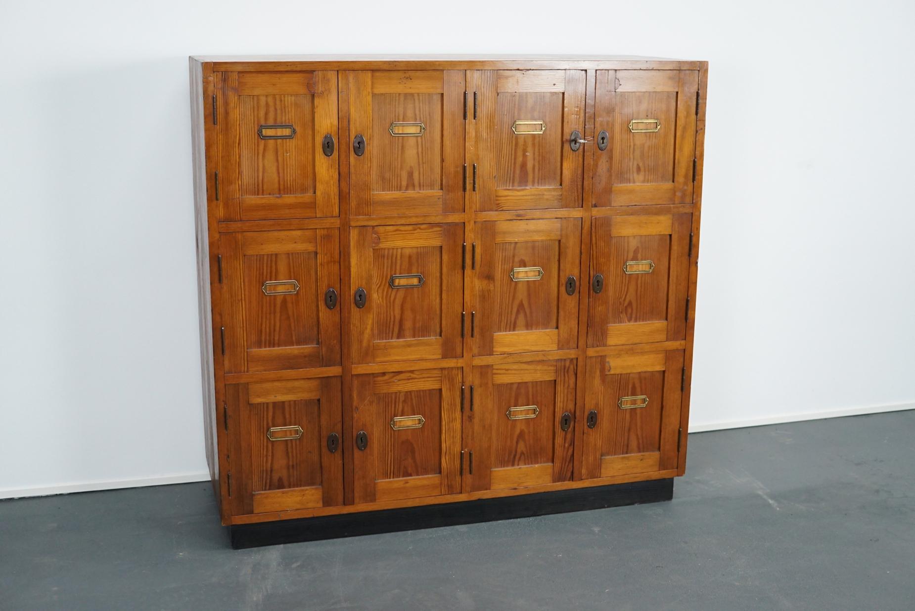 This Dutch pine school locker cabinet was made circa 1930s in the Netherlands.
It features 12-doors/compartments which can be locked separately. 
The interior dimensions of the compartments are: 37 x 25 x 30 cm.