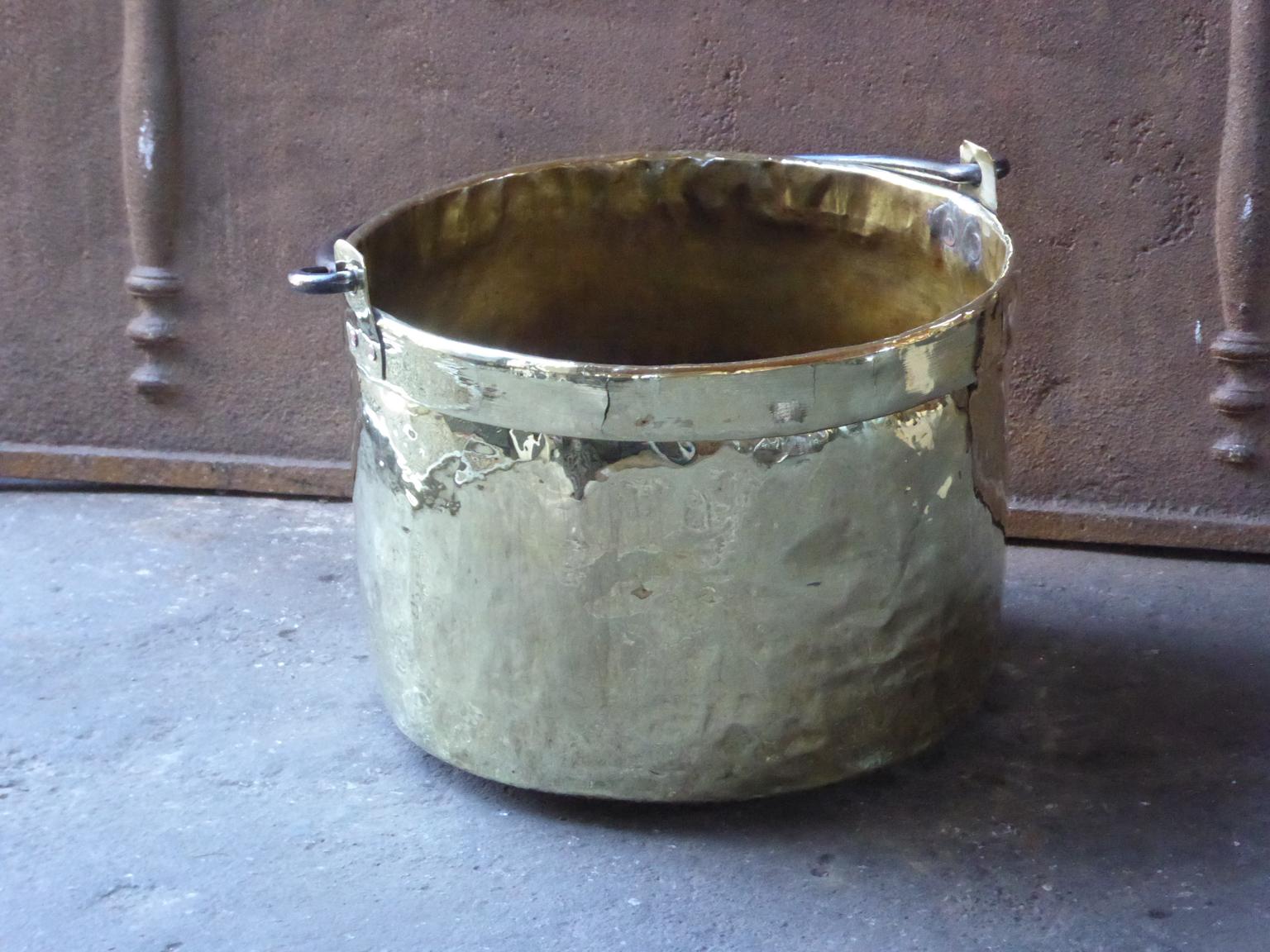 18th century Dutch Louis XV log basket. The firewood basket is made of polished brass and has a wrought iron handle. The log holder is in a good condition and is fully functional. The total width of the log basket, including the handles, is 46 cm