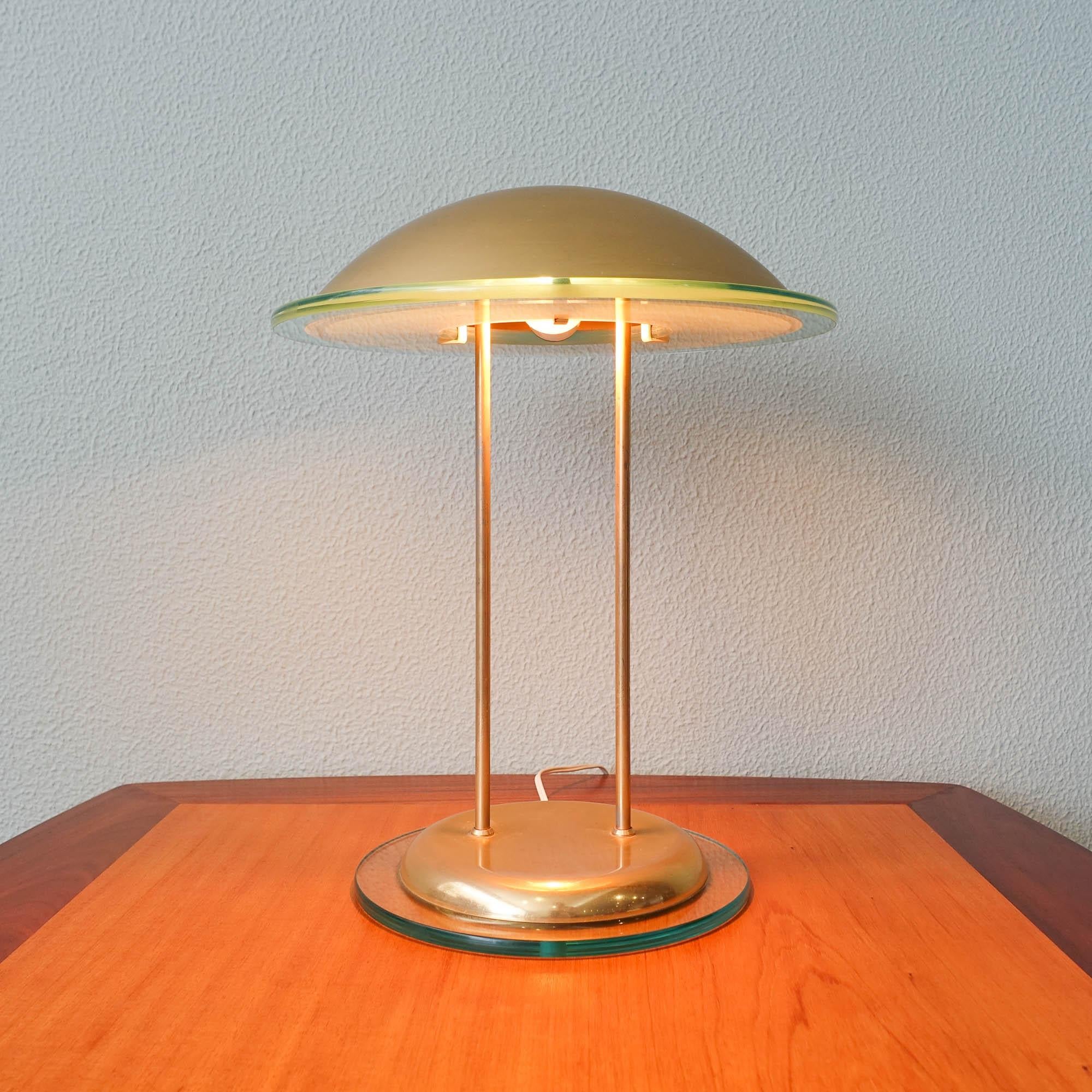 This post modern table lamp was designed and produced by Herda, in Holland, during the 1980's. With a base and lampshade in brass and finishes with a thick greenish glass. In original and good vintage condition.