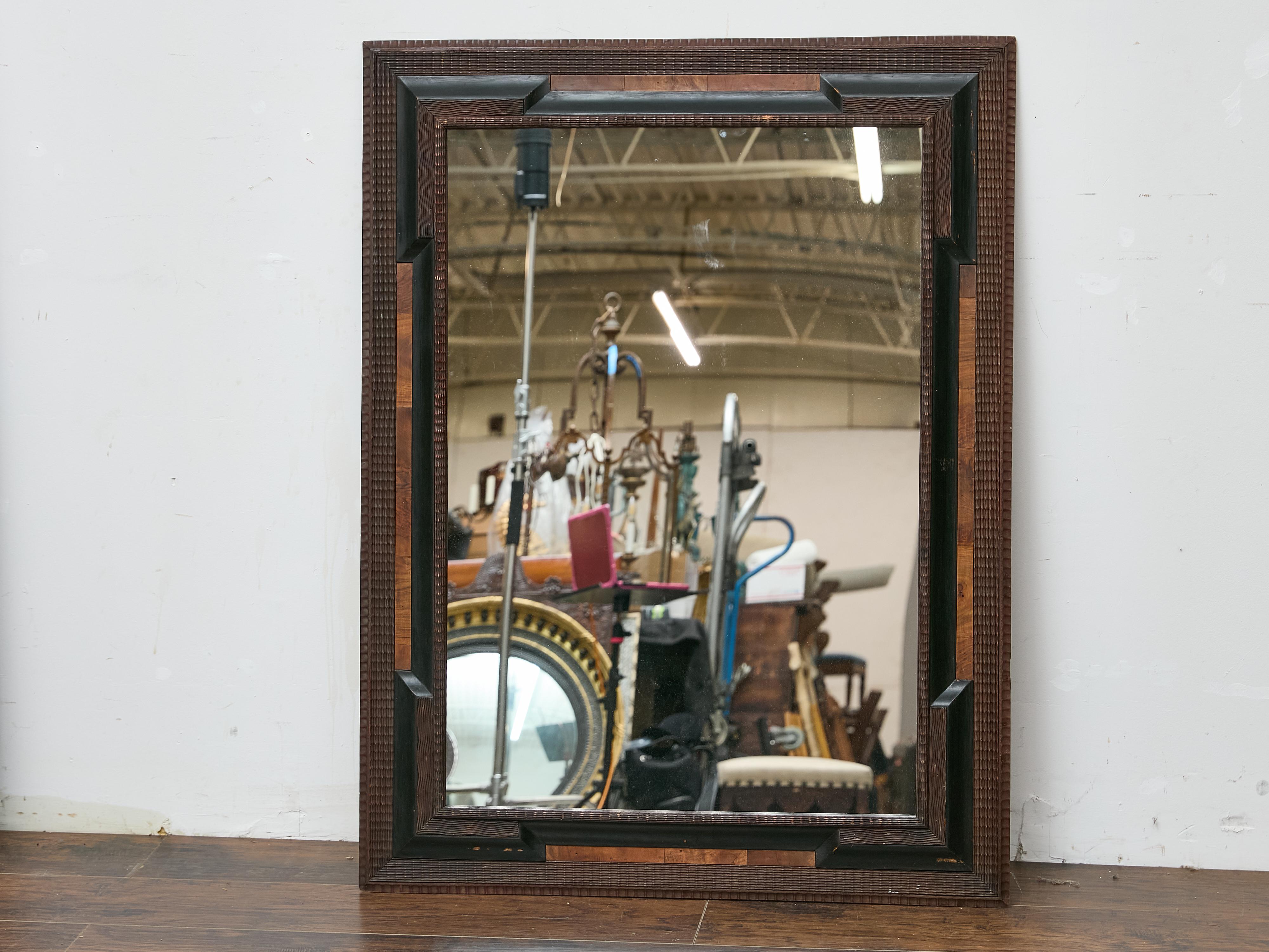 A Dutch mirror from circa 1900 featuring a richly textured ripple-molded frame, crafted in warm-toned brown wood with a fine, regular undulating surface. This classic decorative treatment, typical of Northern European cabinetry and framing, offers