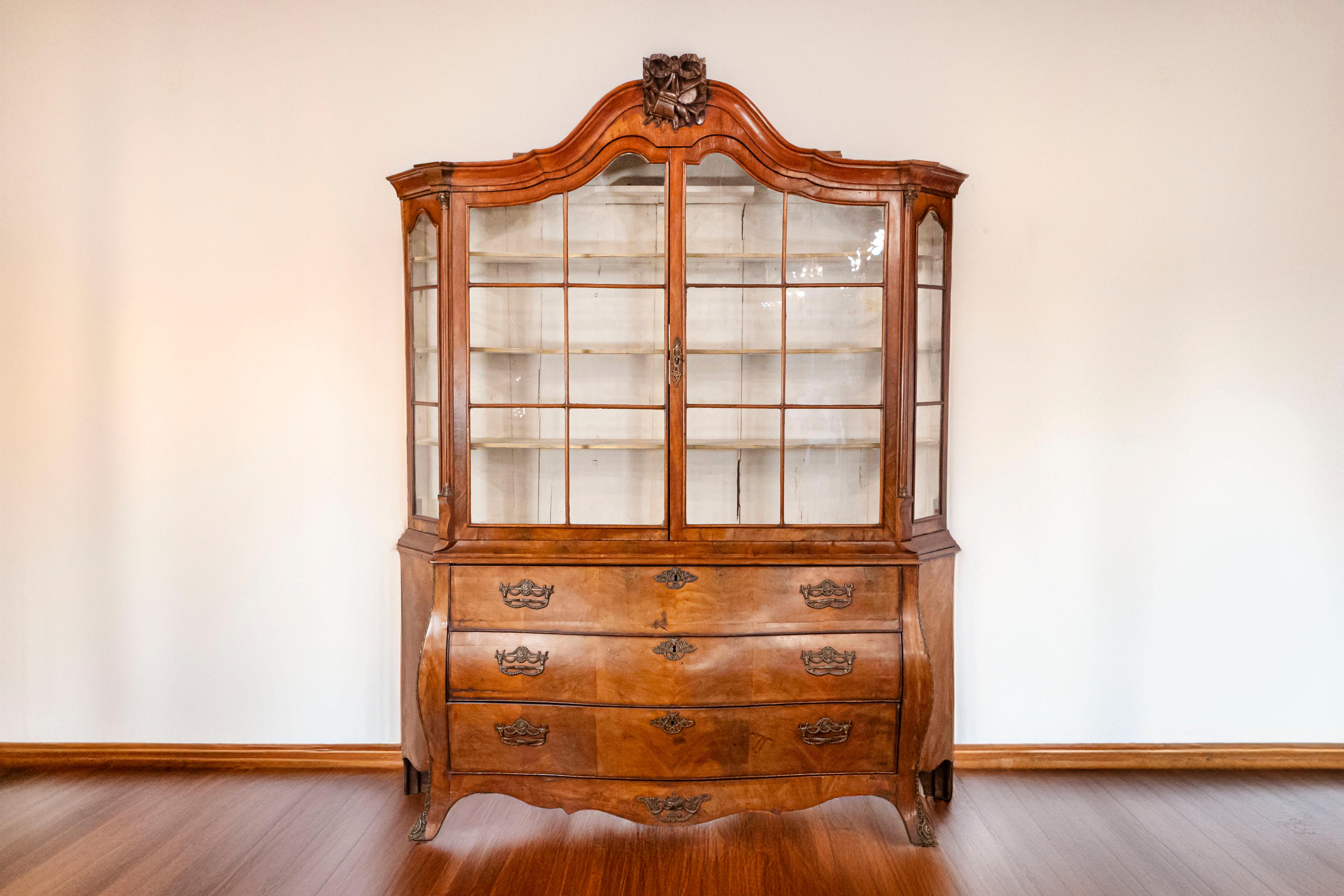 A Dutch Rococo period walnut vitrine cabinet from the late 18th century, with hand carved hunting trophy, glass doors and bombé chest. Born in the Netherlands in the later years of the 18th century, this exquisite Rococo cabinet features a