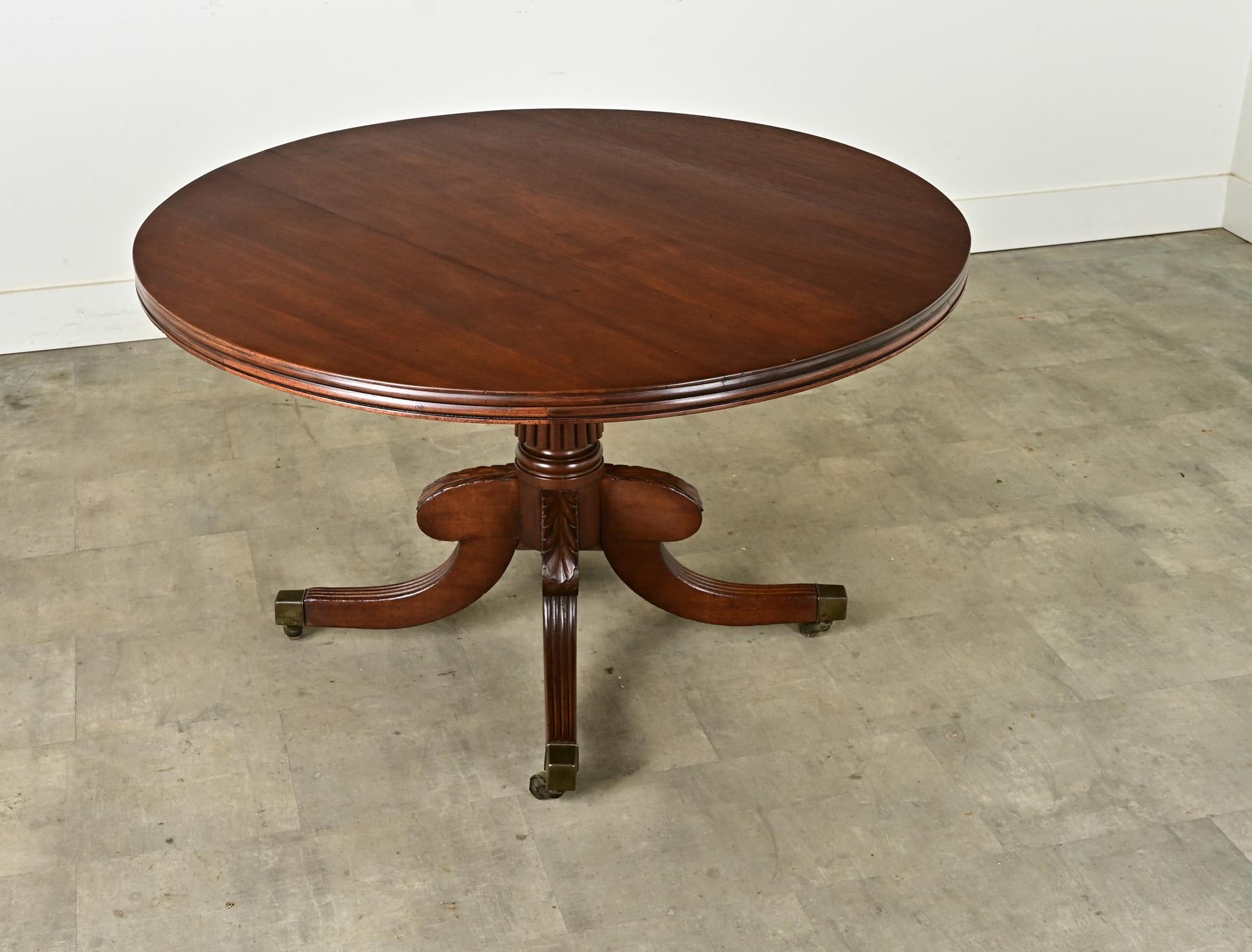 The perfect round table to comfortably seat four people for dining or games. This agile Dutch tilt top table is made of mahogany and easily converts from upright to flat as needed. The pedestal base has a reeded center column with four shaped and