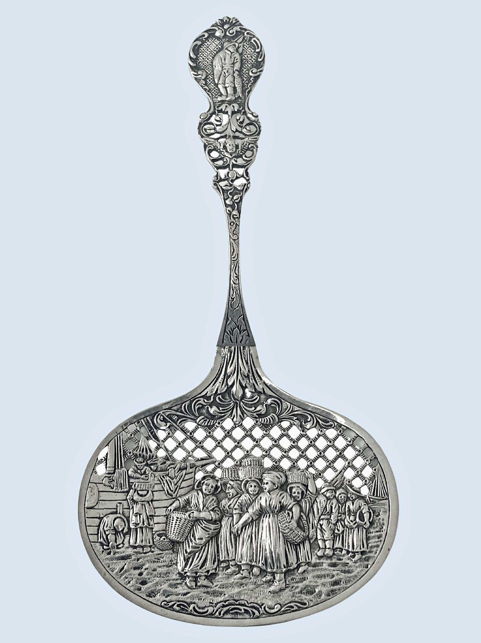 Cuchara de plata perforada y repujada holandesa para servir conservas de bayas C.1916. Soberbia orfebrería que representa una escena de mercado en grupo figurado, friso superior bellamente perforado en un cuenco plano, asa con tallo foliado grabado