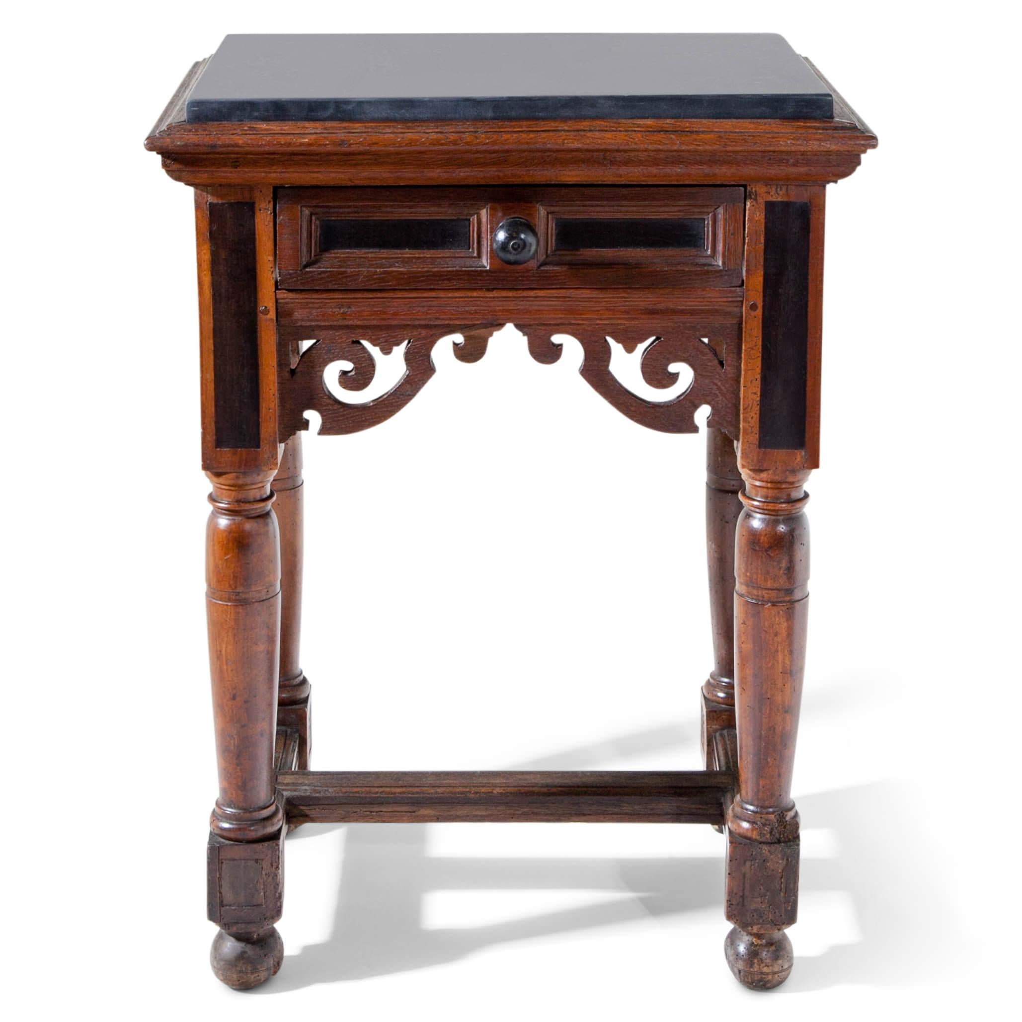 Small side table with one drawer out of oak, standing on four baluster legs with ball feet and a double-T strutting. The tabletop is covered with a black marble plate. Drawer and legs are partly ebonized. Unrestored condition.