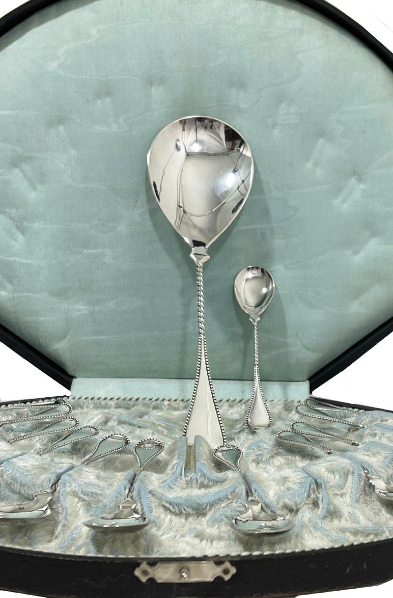 Dutch silver dessert set by Gerritsen, 1907

A set of 12 Dutch silver dessert spoons and a Silver large serving spoon with twisted and oval shaped with pearl rim handle in box 
Dutch silver hallmark of 