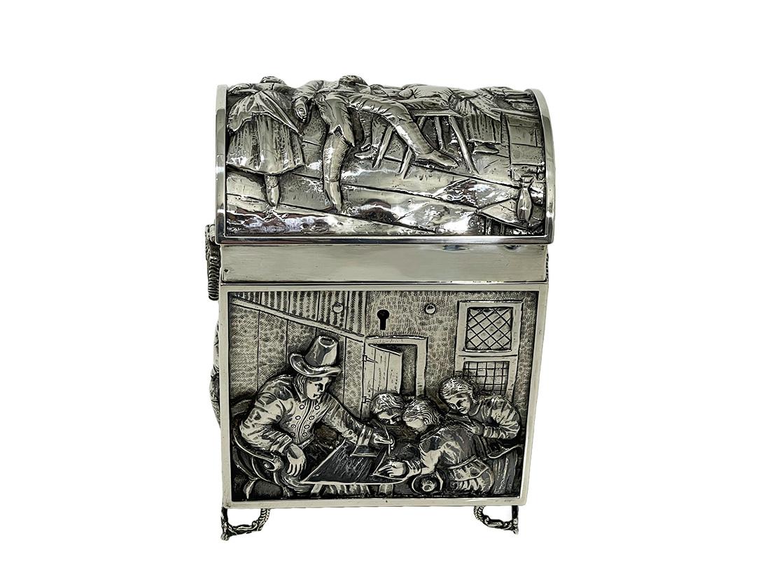 Dutch silver lidded box with 17th century scenes by Jan Steen

A large Dutch silver box with a high round lid, raised on four legs of dolphins. The box decorated in high relief with scenes of the 17th Century by the Dutch painter Jan Steen and