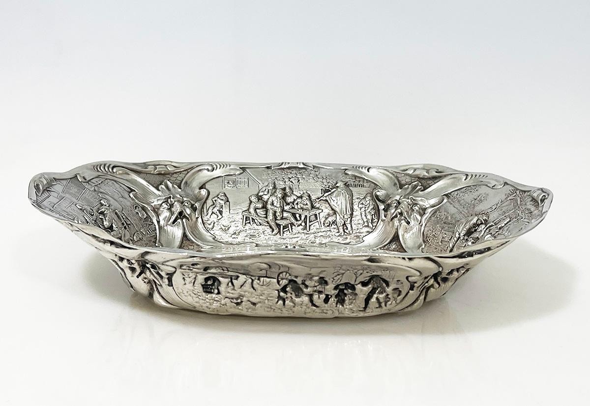 Cuenco ovalado de plata holandesa, panera de Schoorl/ Krot, Amsterdam, fechado en 1928

Precioso cuenco/panera oval con cinco escenas de Jan Steen y una cabeza de animal representada en cada esquina. Estas escenas en altorrelieve de plata proceden
