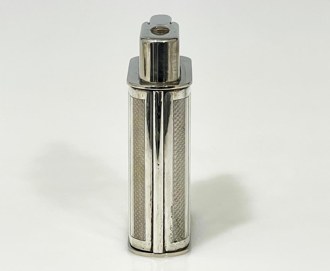 Dutch silver table lighter, 1949

The lighter is a petrol lighter which is equipped with a flint. Top and bottom of chrome metal and the body is surrounded with silver and has a guilloche pattern and has the Dutch silver hallmarks 