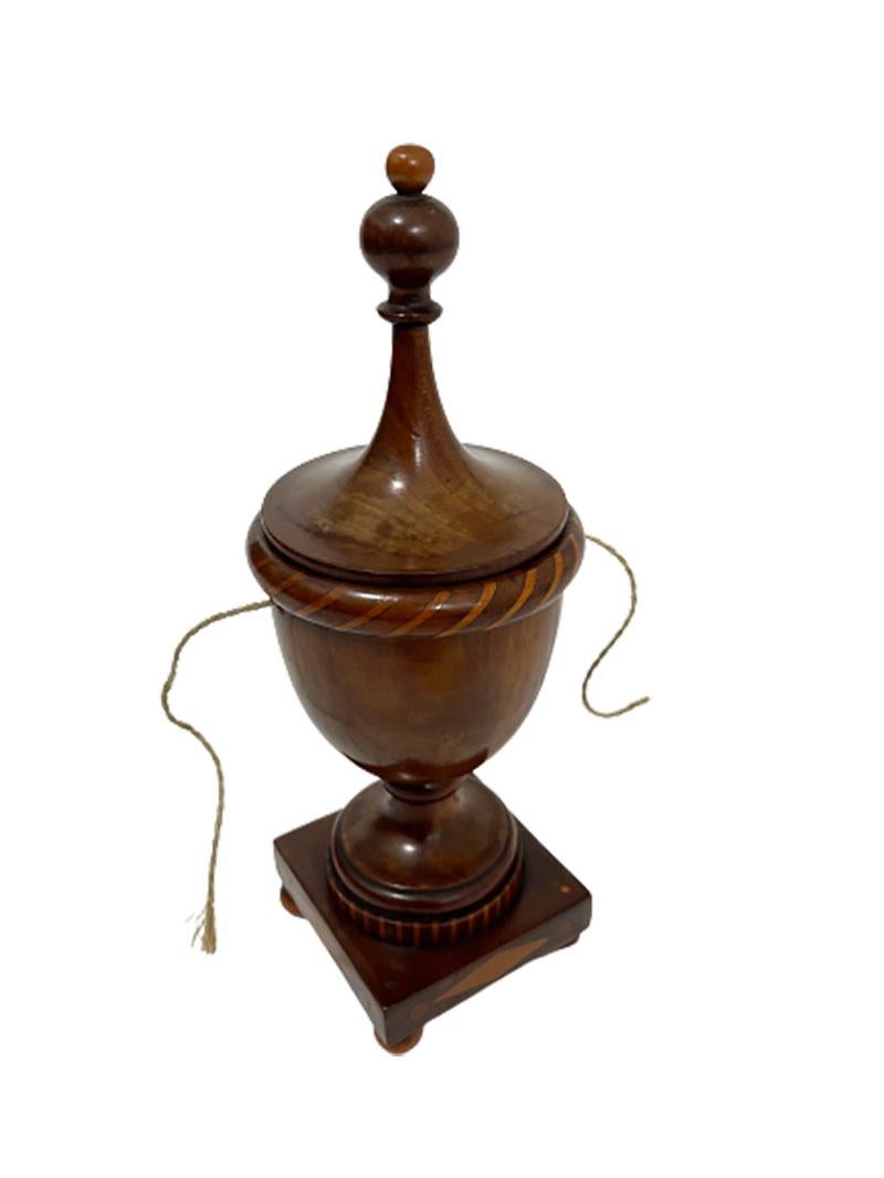 Dutch small 19th Century wooden lidded wool basket

A nut wood with inlay of fruitwood wool basket, raised at 4 ball feet. 
When you were knitting at home, you put the tangle in a suitable container. The open containers were not very useful in