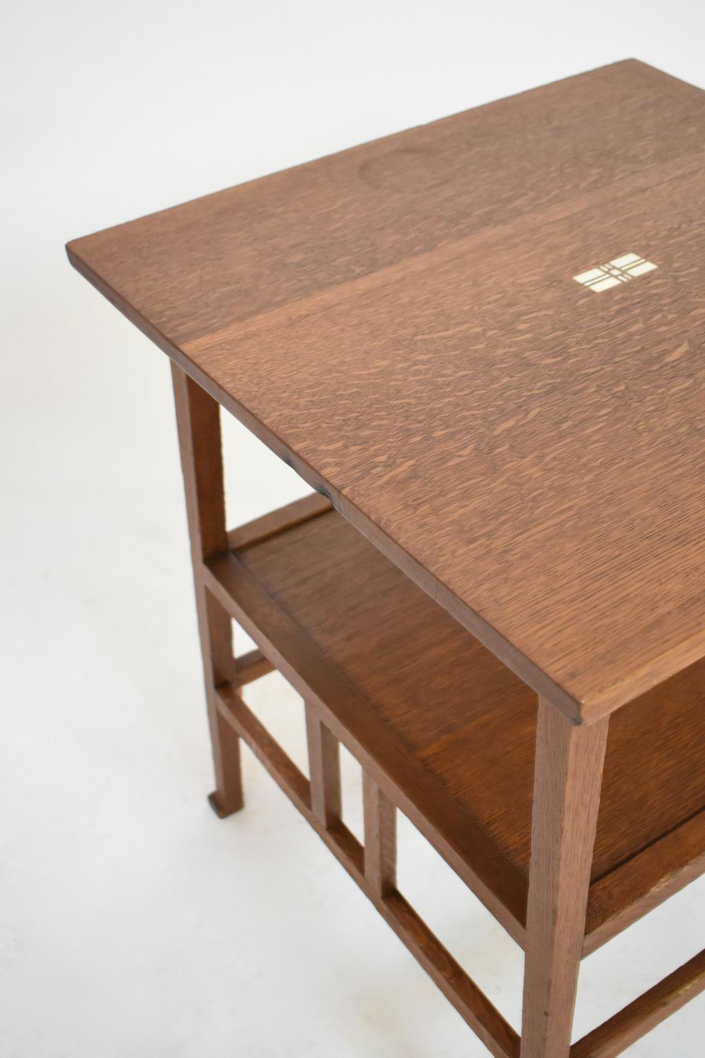 Square oak pedestal table with inlay decoration in the center of the upper shelf, resting on four legs joined by a spacer shelf and an openwork belt, Art Nouveau work (Nieuwe Kinst), attributed of Onder Den Sint Maarten Netherlands, 1910s.