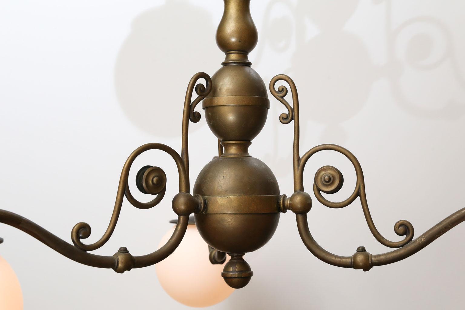 Dutch-style Belgian chandelier in cast brass in a beautifully aged patina. Three lights contained within matte milk glass globes, circa 1910-1930. Newly wired for use within the USA. Three medium-base (Edison) size sockets. Includes chain and a