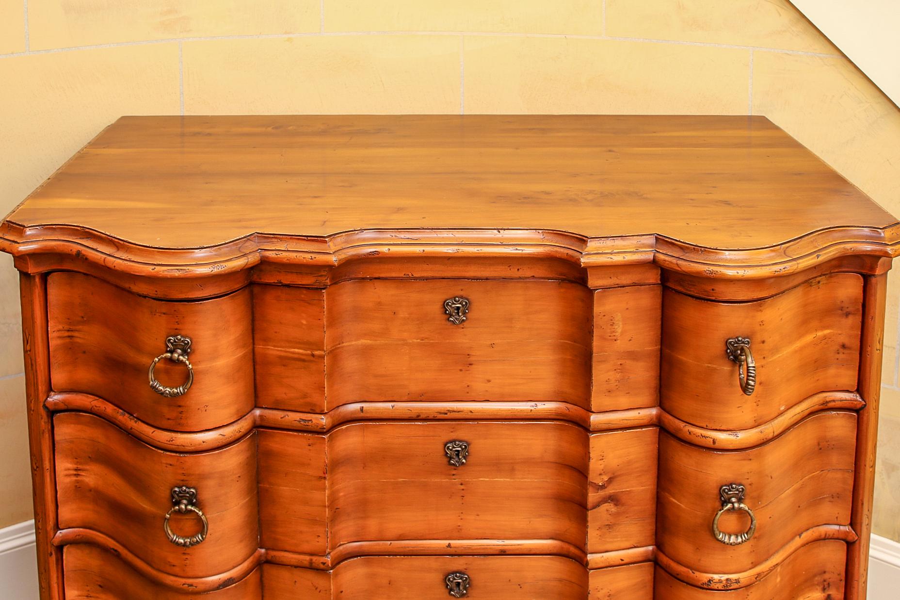 Dutch-style chest by Alfonso Marina [Mexico City] with serpentine front, four drawers, bold moulded trim, brass drop pulls and escutcheons, raised on bun feet.

Condition: Good condition with expected signs of use and wear including some light