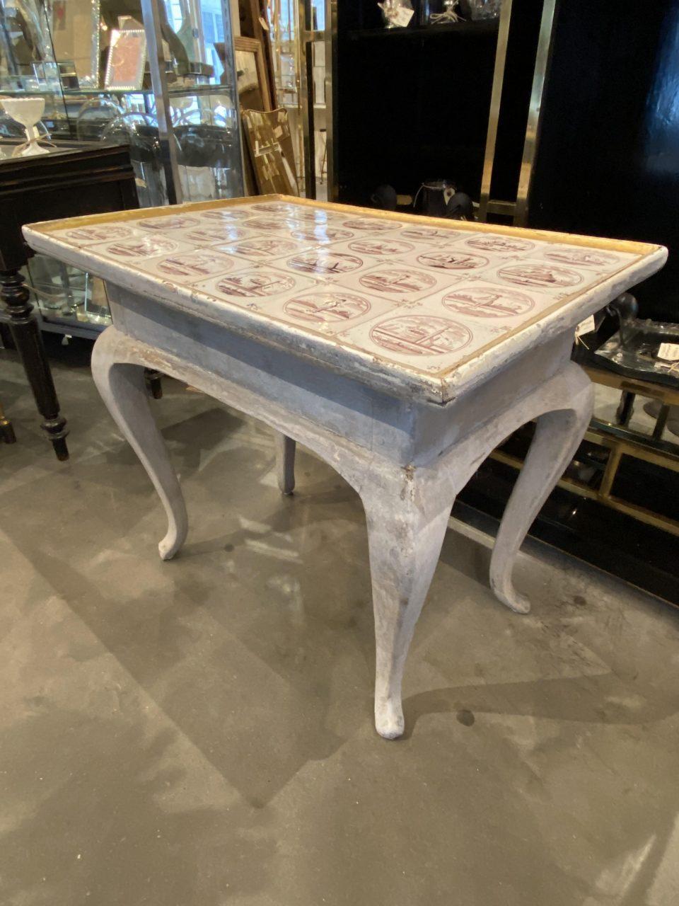 Antique tile top table, with Dutch tiles, dated around 1800. Roccoco style elegant curved legs, and a wonderful palest grey paint with gilt edging. Aubergine and white tiles. Pretty patina.