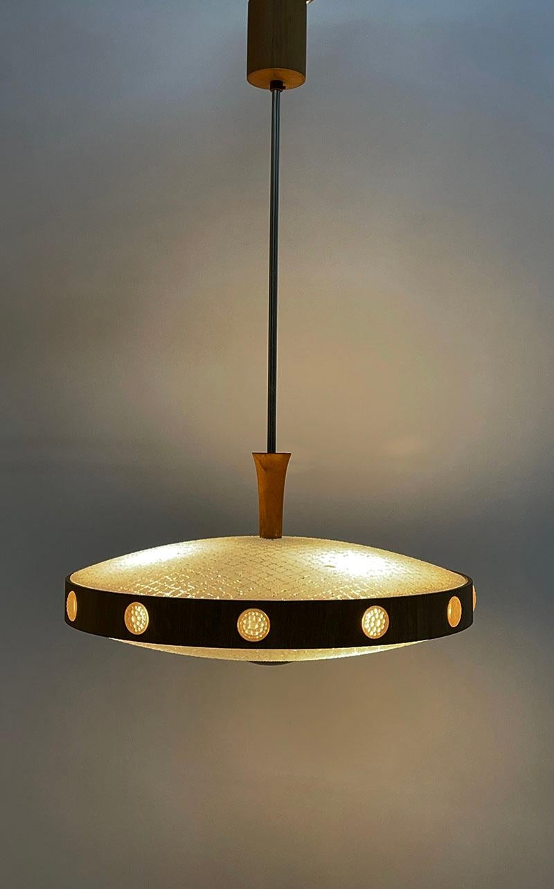 Dutch Ufo space age ceiling lamp, 1960s

This Ufo Space age shaped ceiling lamp is attributed to the manufacturer Philips, The Netherlands. The lamp is made of round glass with a pattern at the top and bottom. In between a band of beech with round