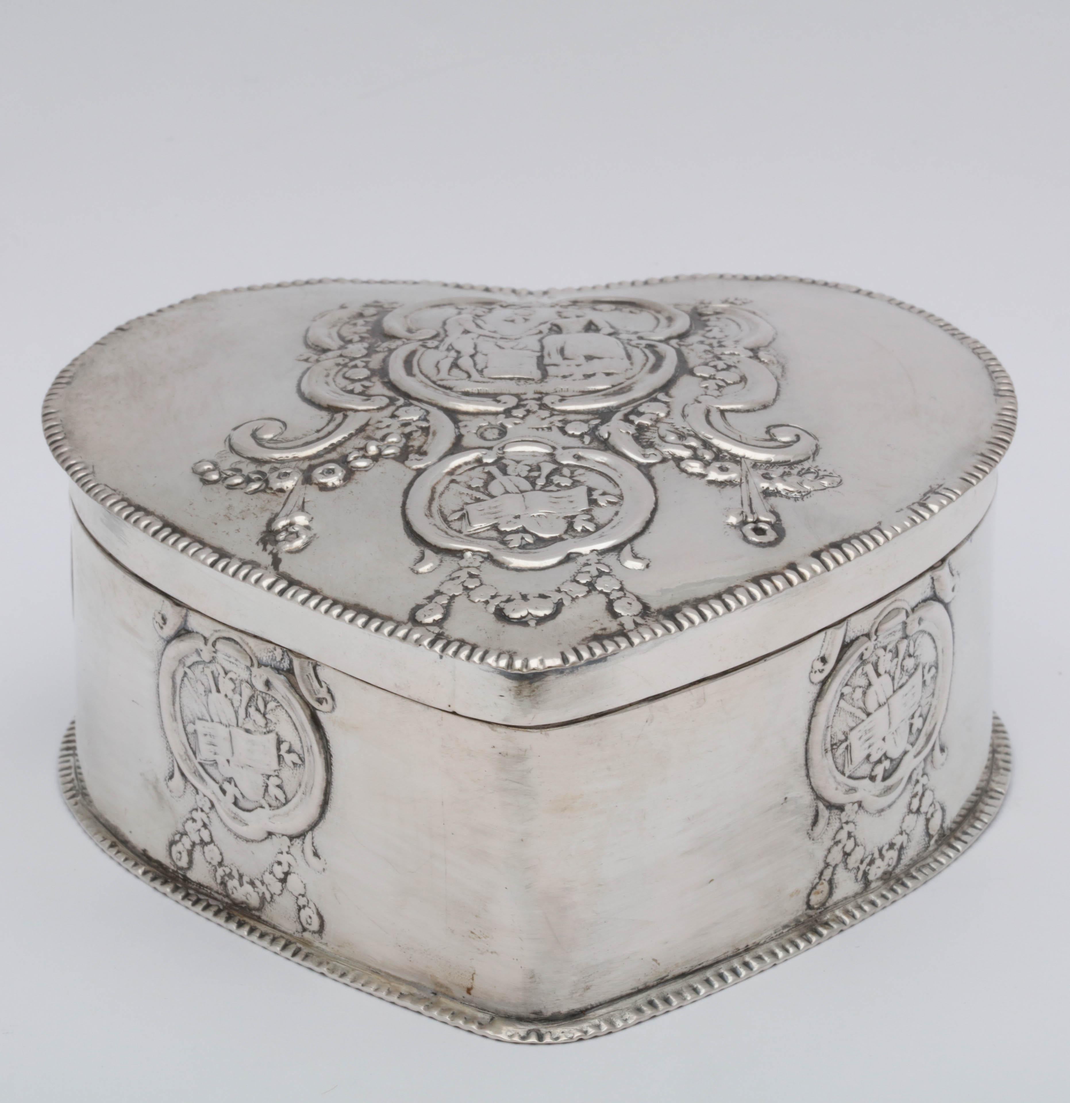 Dutch, Victorian, Continental silver (.800) heart-form box with hinged lid, Netherlands, year-marked for 1901. Scene of a man and woman in center of lid; decorated with musical instruments, etc. on outer sides. Measures 4 1/4 inches across (at