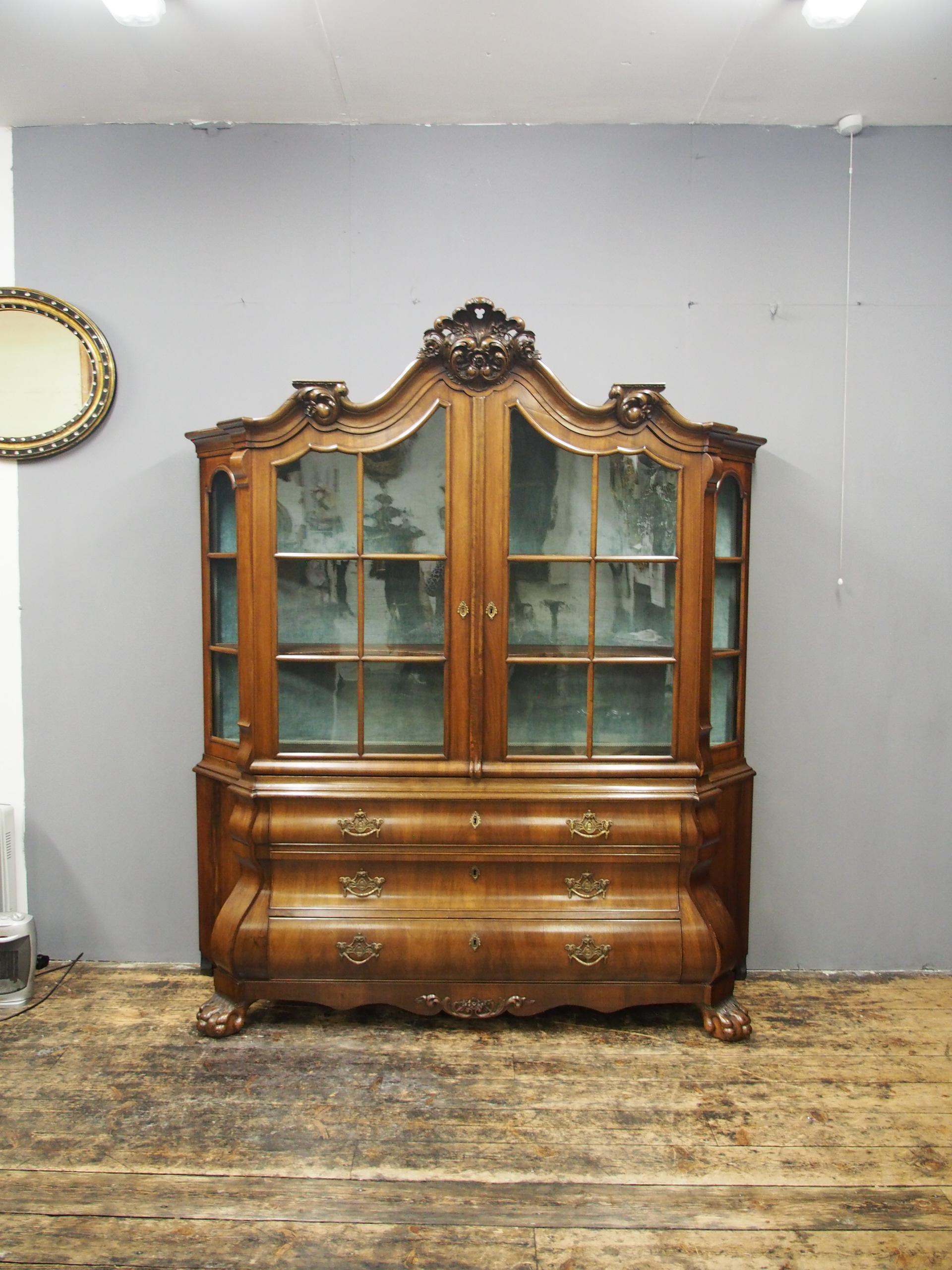 Victorian Dutch walnut display cabinet or bookcase, circa 1850. The shaped domed top has a moulded cornice and is surmounted by a pierced and carved foliate cartouche. The twin astragal glazed doors open to an interior with a velvet lined back and