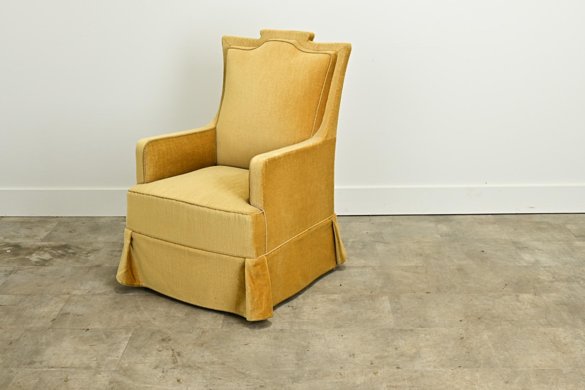A comfortable vintage mohair armchair from the Netherlands. This armchair is upholstered and skirted in a mustard colored mohair fabric with a braided trim. Be sure to view the detailed images to see the current condition of this vintage armchair.