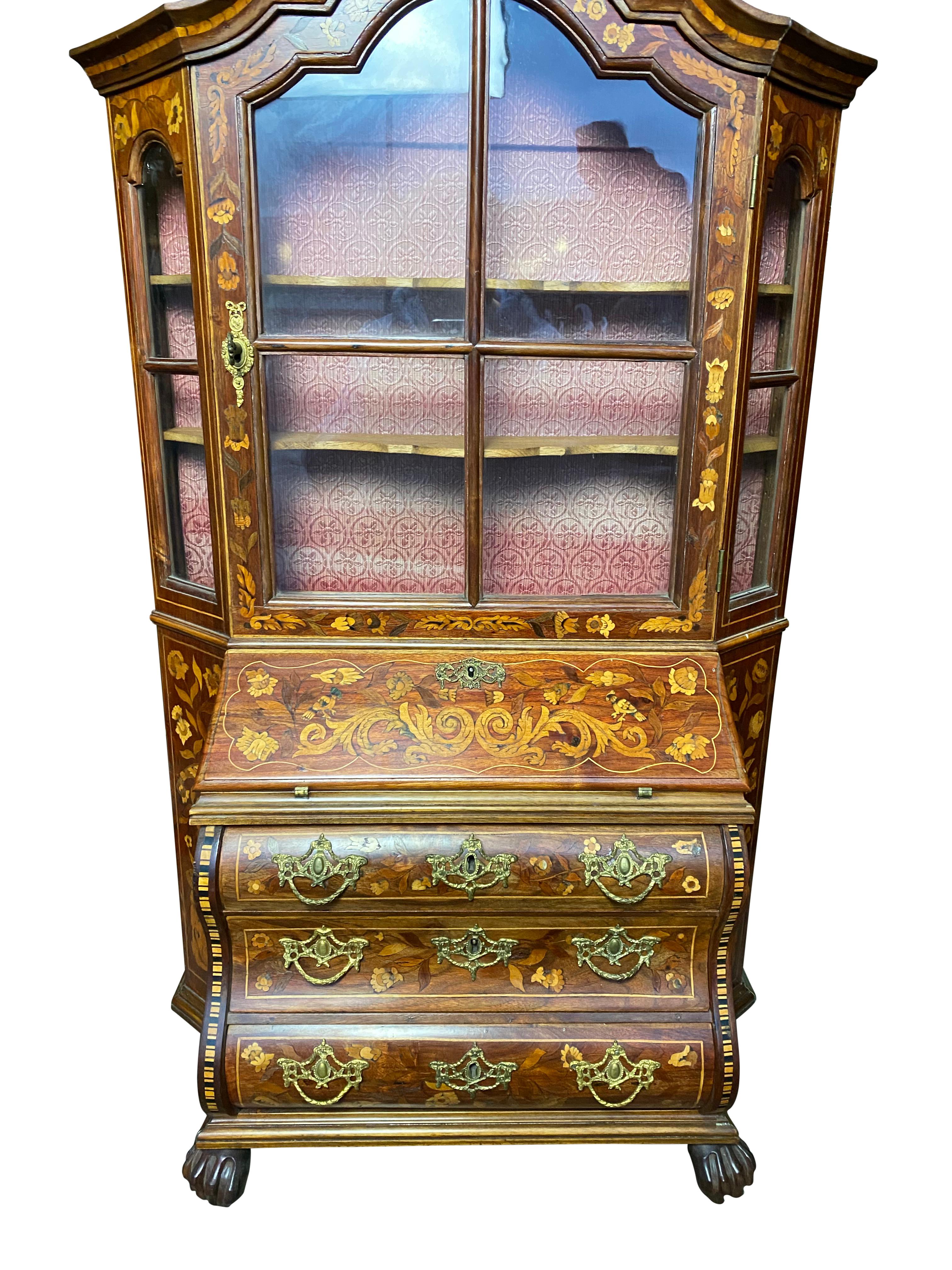 An 18th century Dutch walnut secretaire bookcase with undeniably striking colors. Several shelves open up to various platforms to provide a beautiful interior with a lock and key mechanism on the main door. A beautiful floral design extends over the