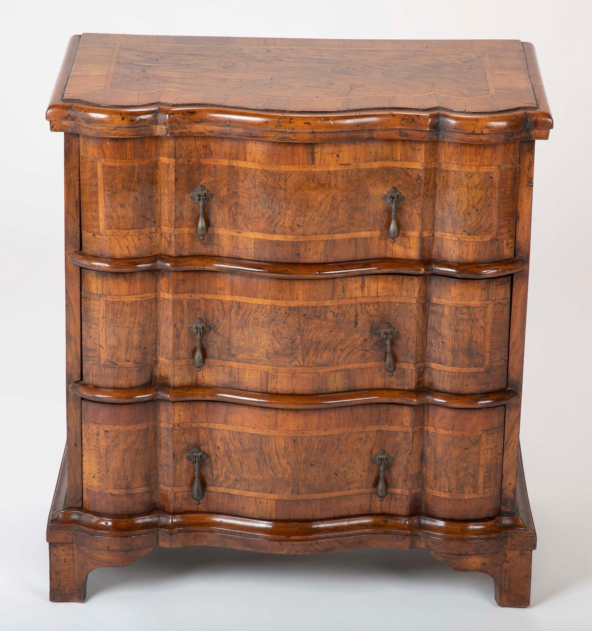 A great looking small scale Italian Baroque style three-drawer commode with burl walnut veneer and fruit wood inlay. The serpentine drawer fronts giving this piece a sexy look, with teardrop bronze pulls. The interior retaining the original paper
