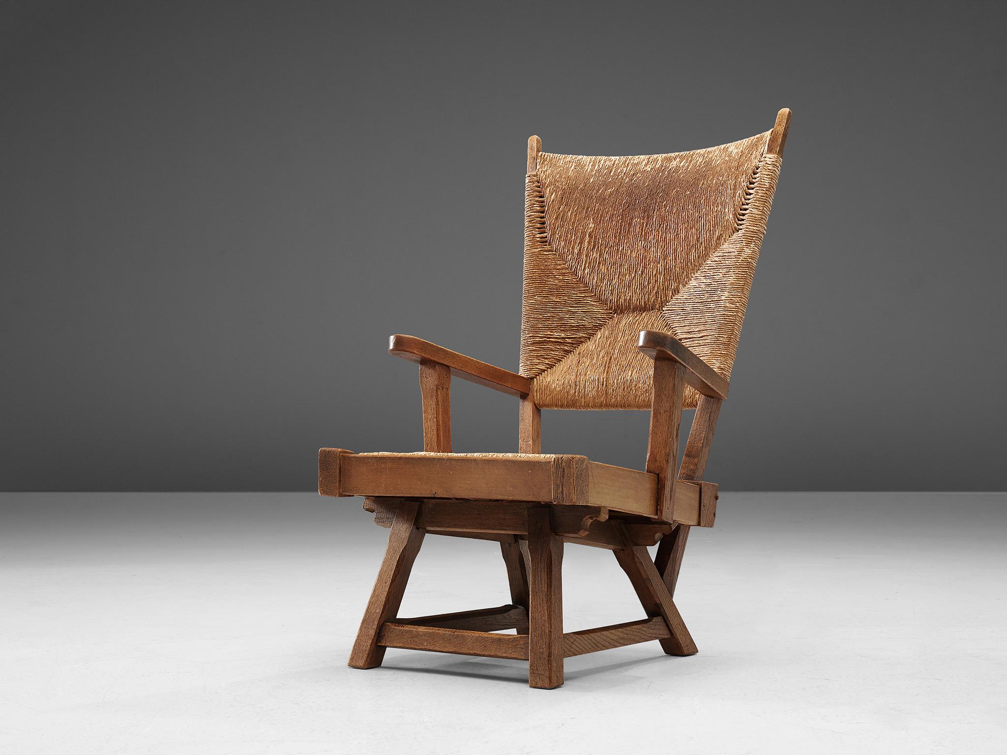 Wicker amchair, oak and cane, Netherlands, 1930s. 

This robust chair has a warm but regal character because of its high back. The frame with tilted seating, executed in a centered woven cane pattern, insures comfort for the sitter. The exposed