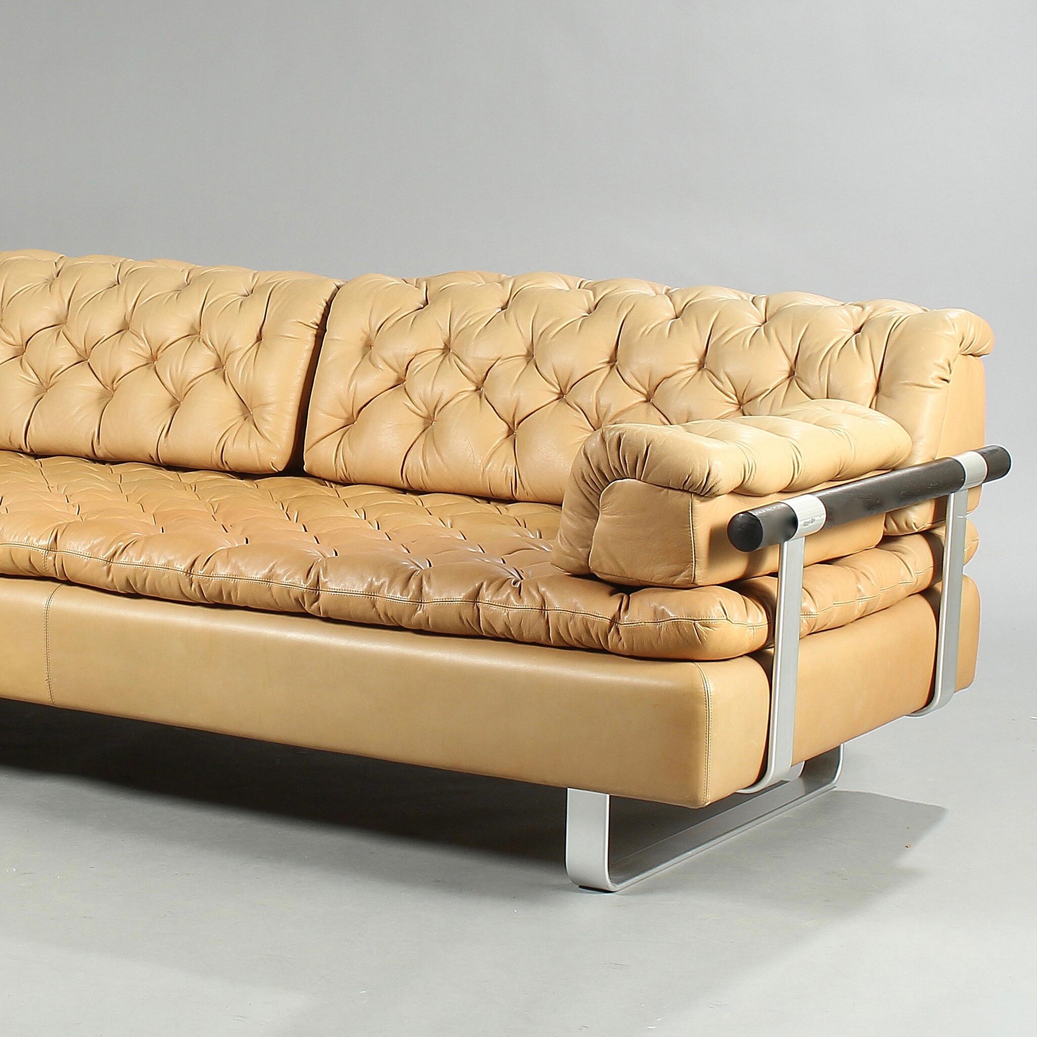 A daybed upholstered with natural colored leather, back and side with aluminium frame and dark oak pole. Manufactured and marked by DUX. Sweden. Measures: L. 206, D. 90 cm.
