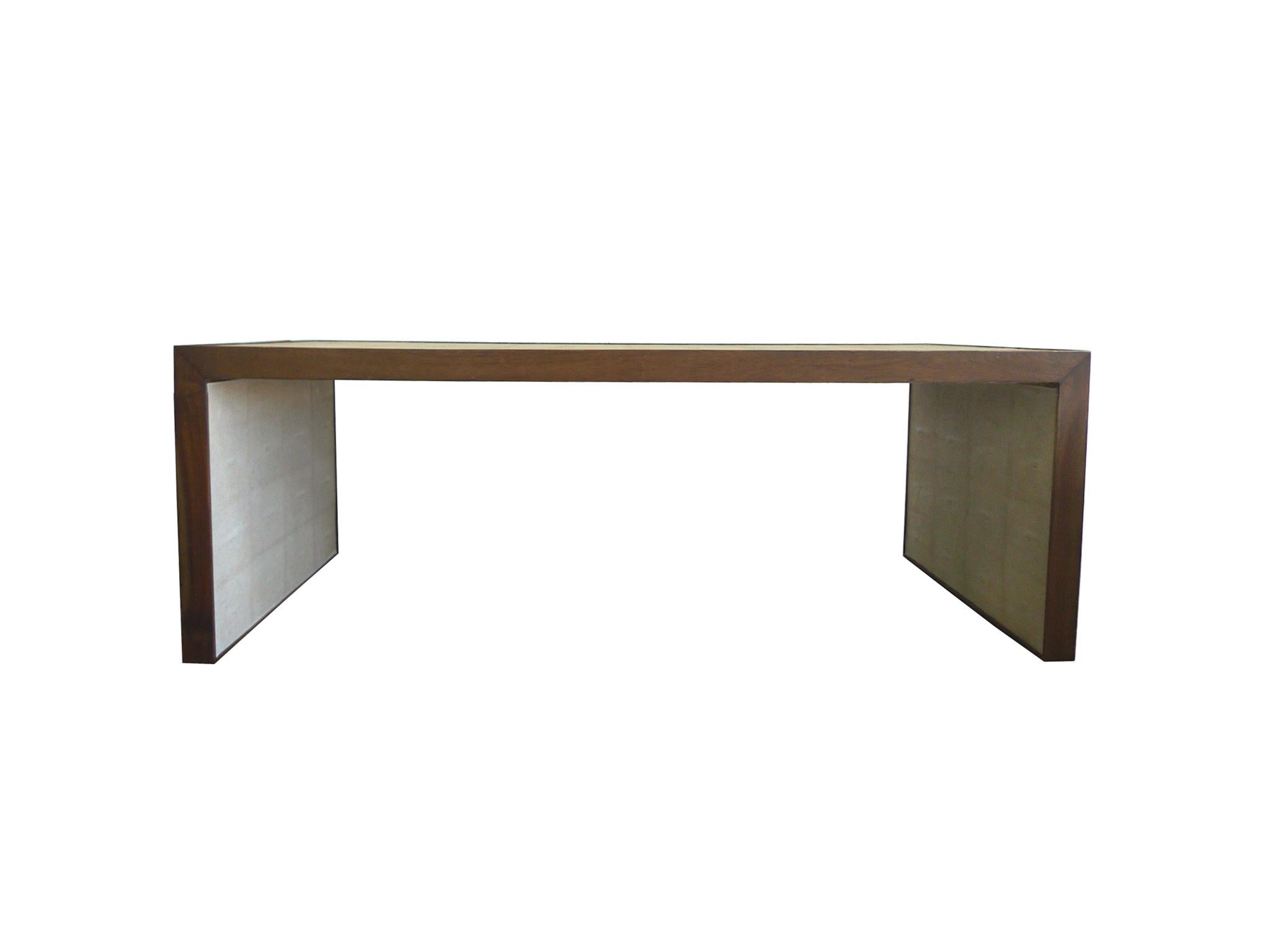 This handsome coffee table was made by Dwell Studios. It is comprised of a rectangular frame crafted from walnut and wrapped in a beige faux shagreen. The walnut is visible on the sides as an elegant brown trim. Simple in form and with smooth, sleek
