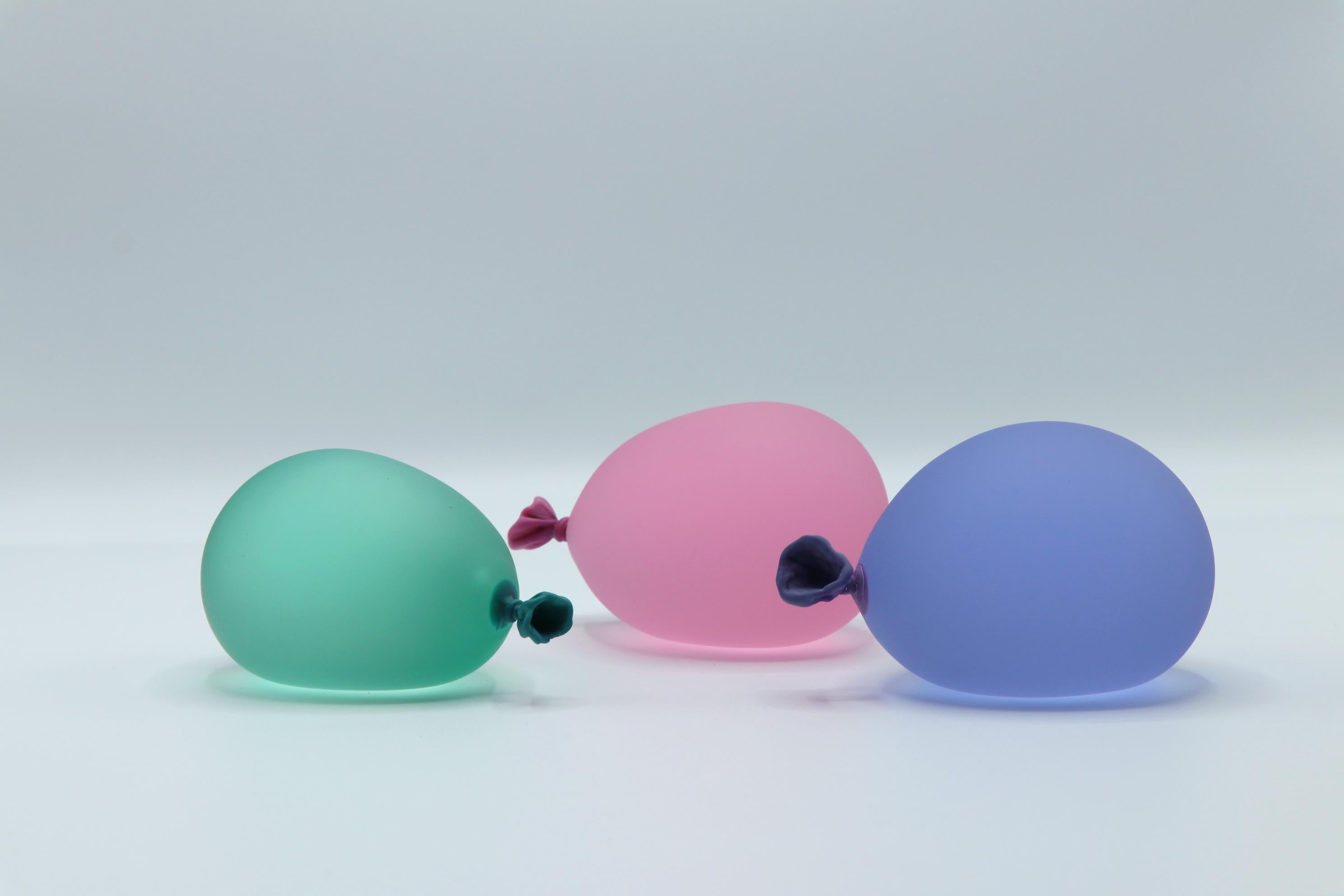 Set of 3 hyperreal glass water balloon sculptures by Dylan Martinez. Made of 100% hot-sculpted glass. 

Dylan Martinez’s hyperrealistic water balloons are made of solid sculpted glass sandblasted and acid-etched to resemble real water balloons. The