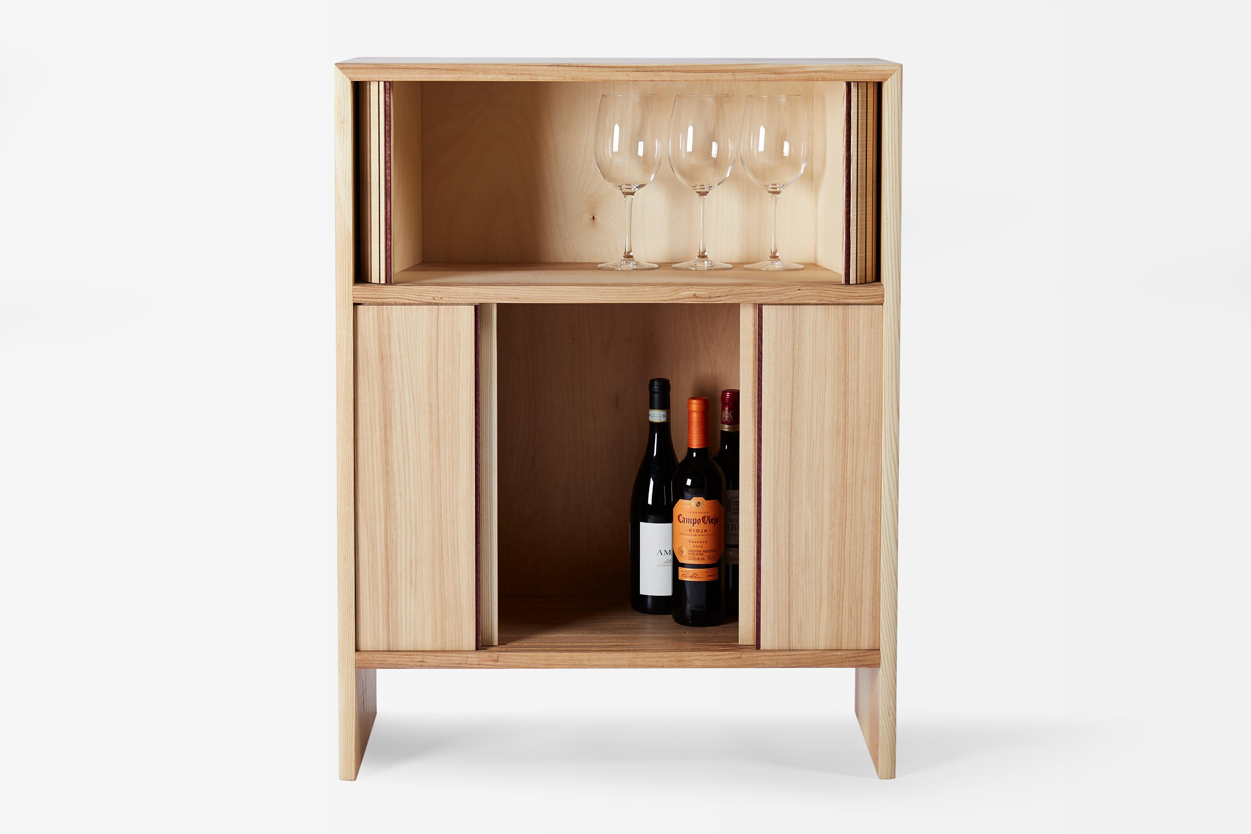 Wine Cabinet II is handcrafted using White Ash and Purple Heart. The lower half has four sliding doors to allow for easy access to all of your bottles. The top section of this cabinet includes a tambour door to store all of your glasses, coasters,