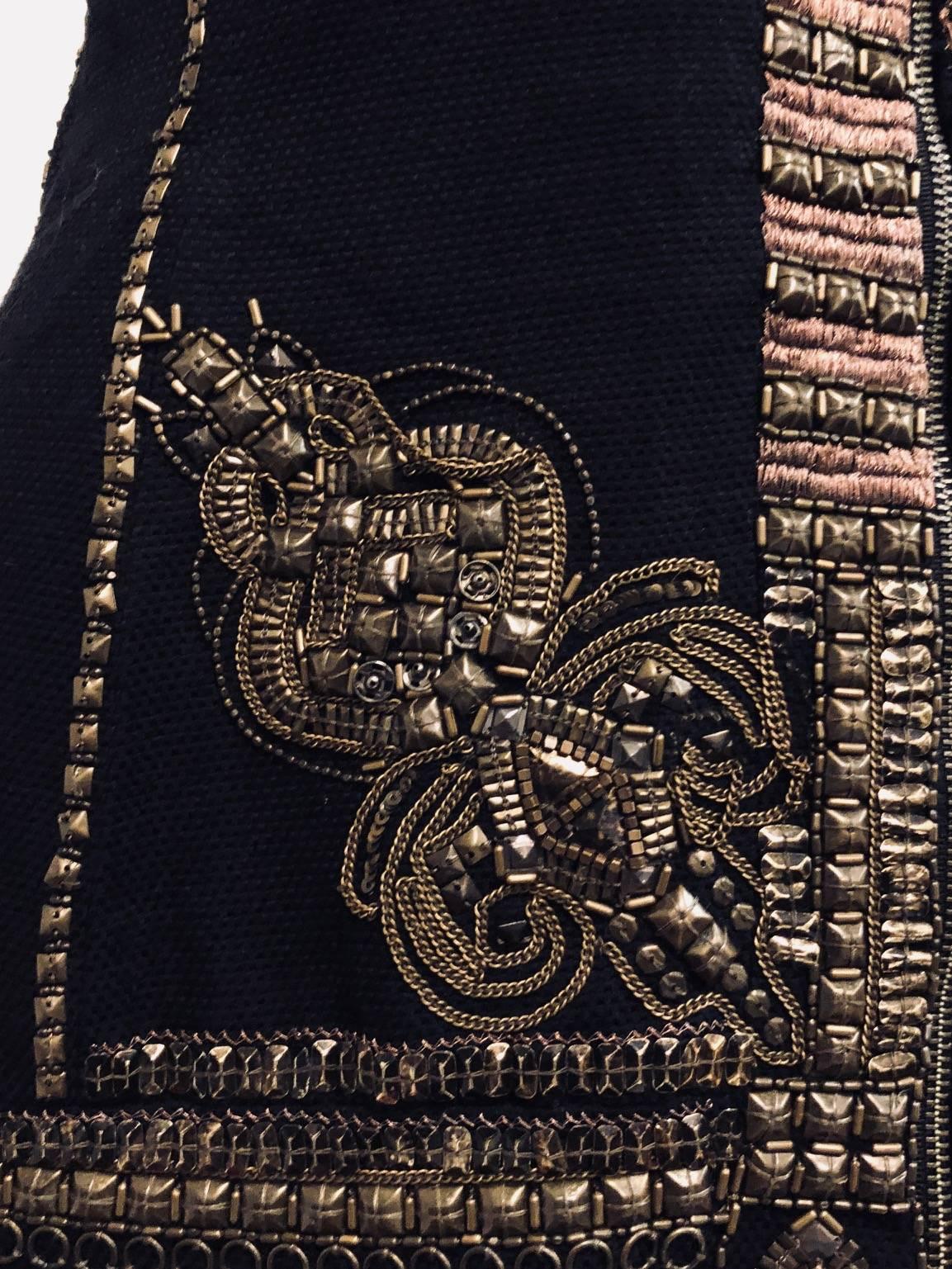This Dries van Noten black wool and cotton blend vest contains intricate designs of beads and different metal ornaments on the front and back of this vest.   The multi layered bronze tone metal decorations on the front closure of this vest also