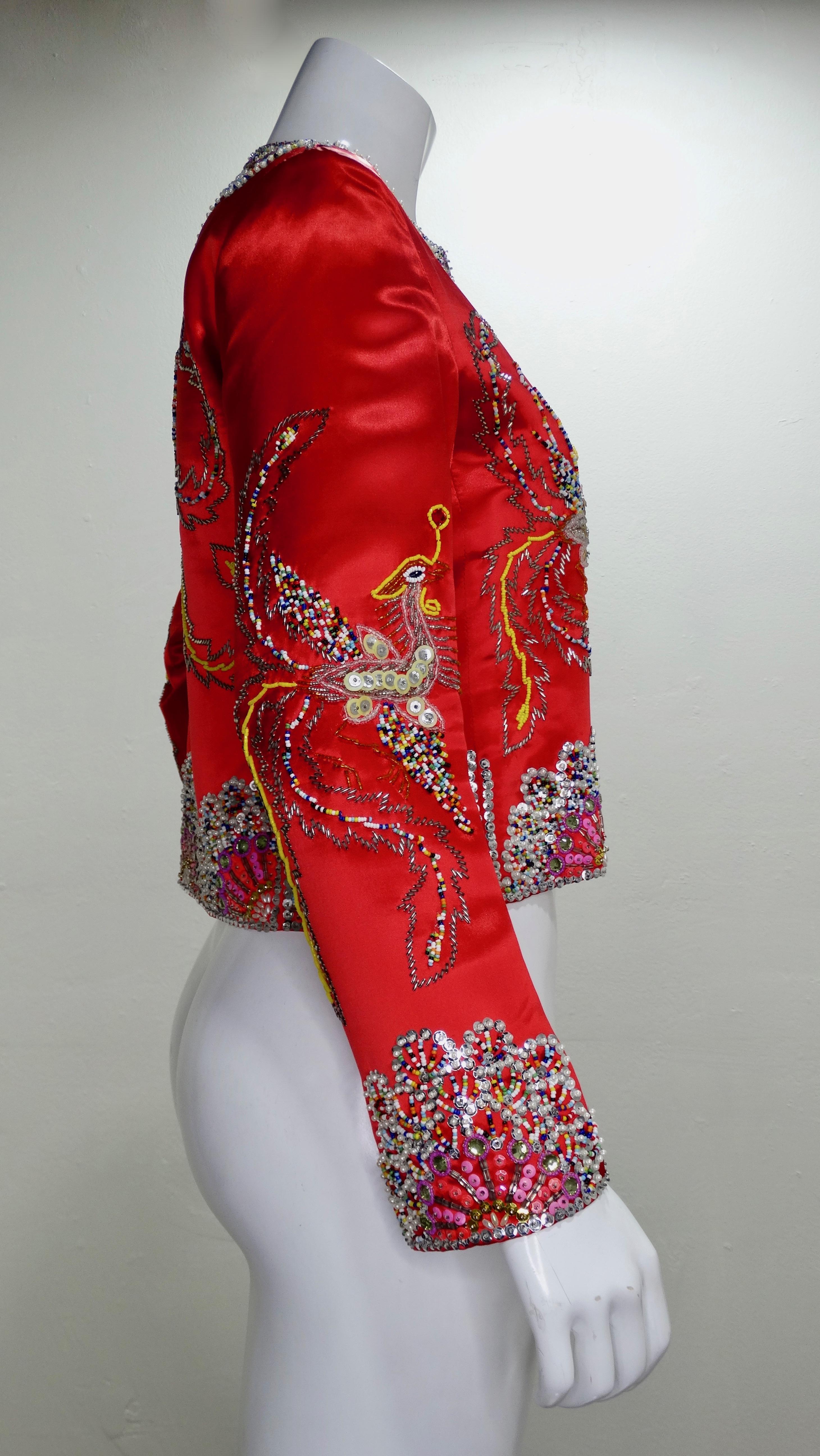 Vous parlez d'une véritable pièce vintage ! Conçue par Dynasty vers les années 1960, cette veste courte en satin rouge est entièrement perlée à la main d'une variété de paillettes, de strass et de perles colorés pour former des motifs Phoenix sur