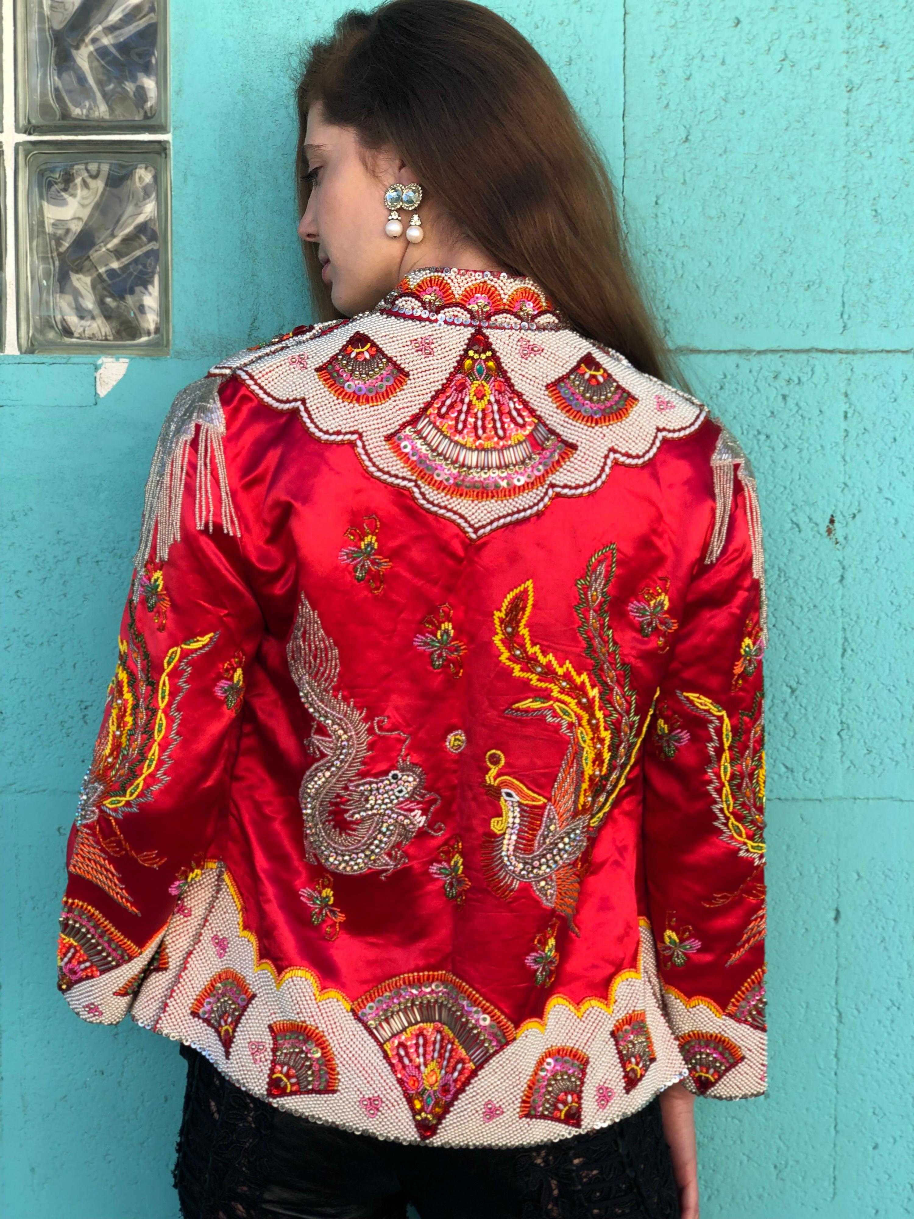 Talk about a true vintage piece! Designed by Dynasty circa 1960s, this red satin jacket is completely hand beaded with a variety of colorful sequins, rhinestones and pearls to form various Phoenix and Dragon motifs on the front and back. Jacket