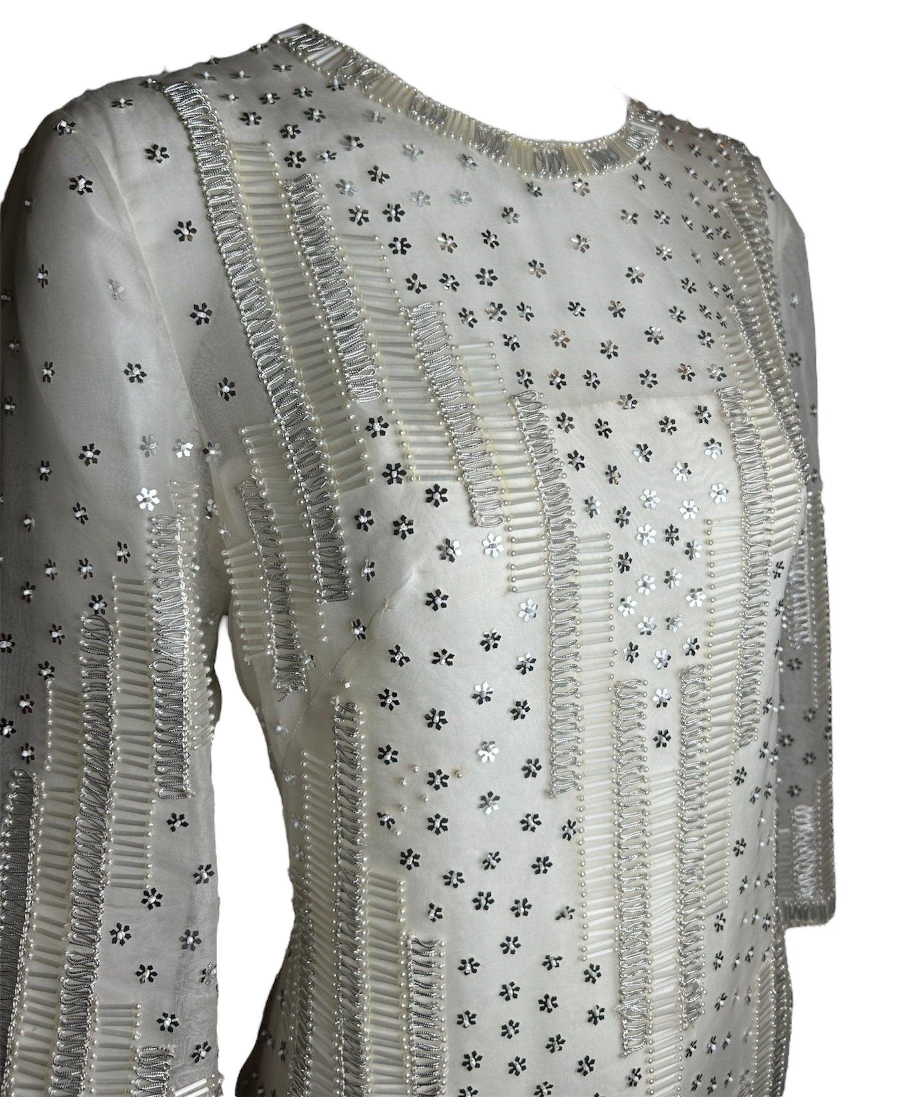 Éthérée et royale, cette robe de style kaftan peut être décrite comme un éclat brillant qui peut illuminer n'importe quelle pièce. Les paillettes étincelantes associées à des perles nacrées donnent à cette robe une allure angélique. Le perlage