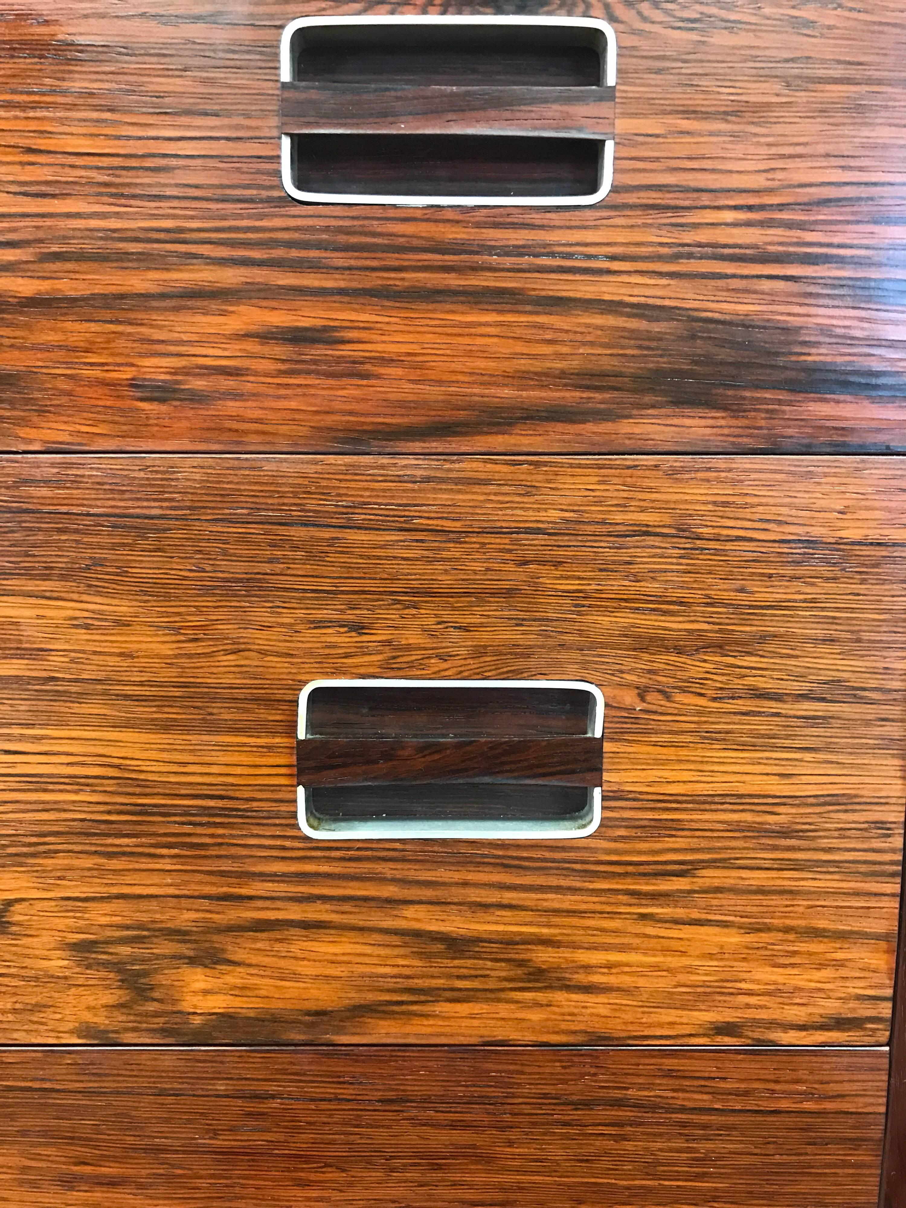 Midcentury rosewood five drawer tall chest of drawers by Dyrlund. Features beautiful wood graining and inset metal pulls. All vendor hallmarks are present.