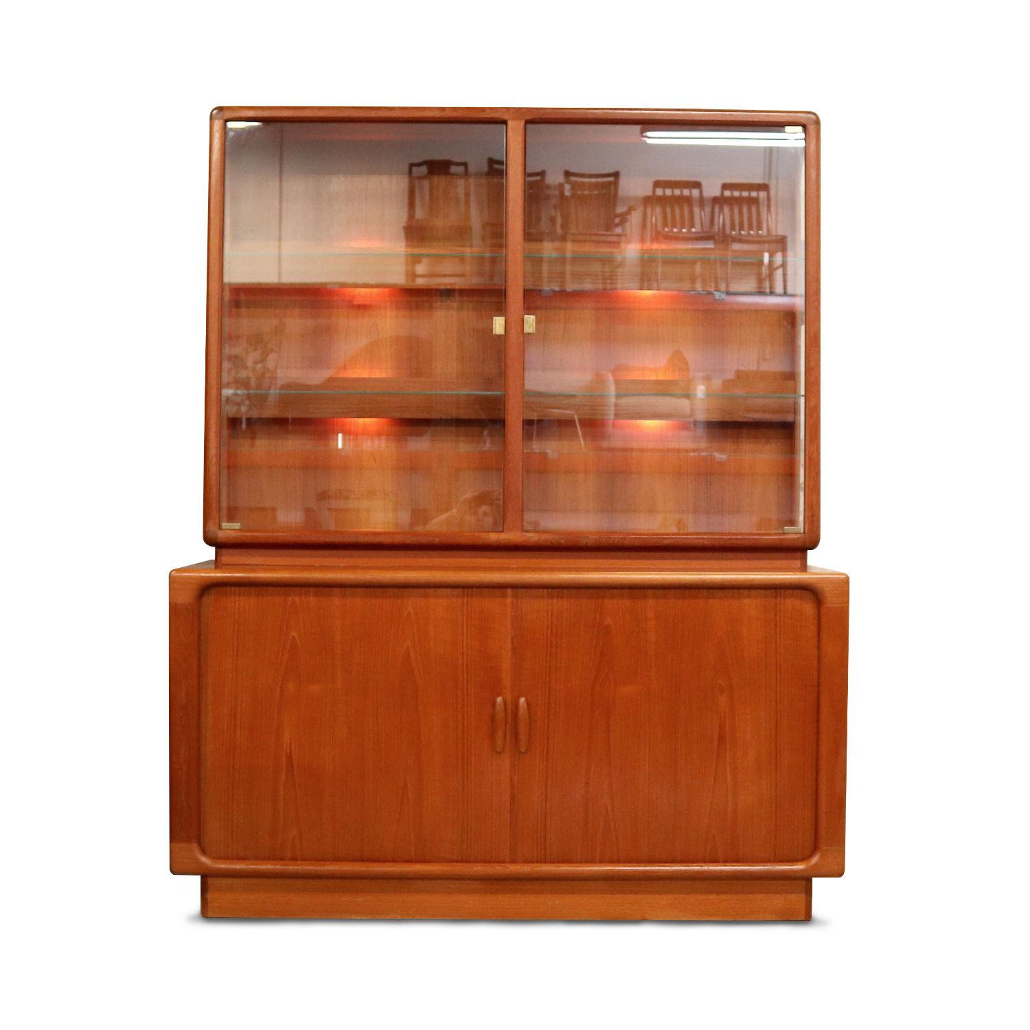 Two-piece Danish modern teak china cabinet with lighted display. The china cabinet by Dyrlund features exquisite styling and craftsmanship throughout. The unit consists of two stacked pieces, a lighted hutch top and buffet base. The gorgeous glass