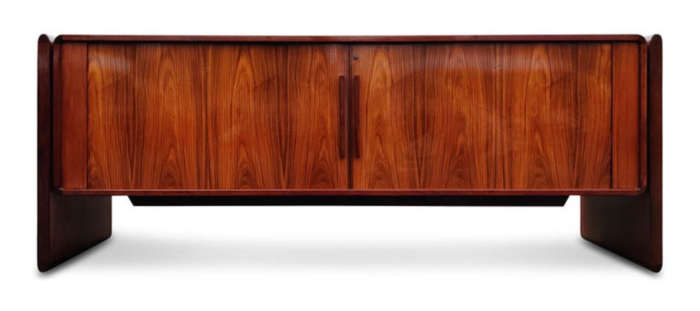A striking Danish Modern rosewood cabinet or credenza circa late 1970s or early 1980s. Features rich rosewood color and dramatic and active grain. Tablet-like legs support a cabinet with finely crafted tambour doors. Doors open to reveal 3 drawers