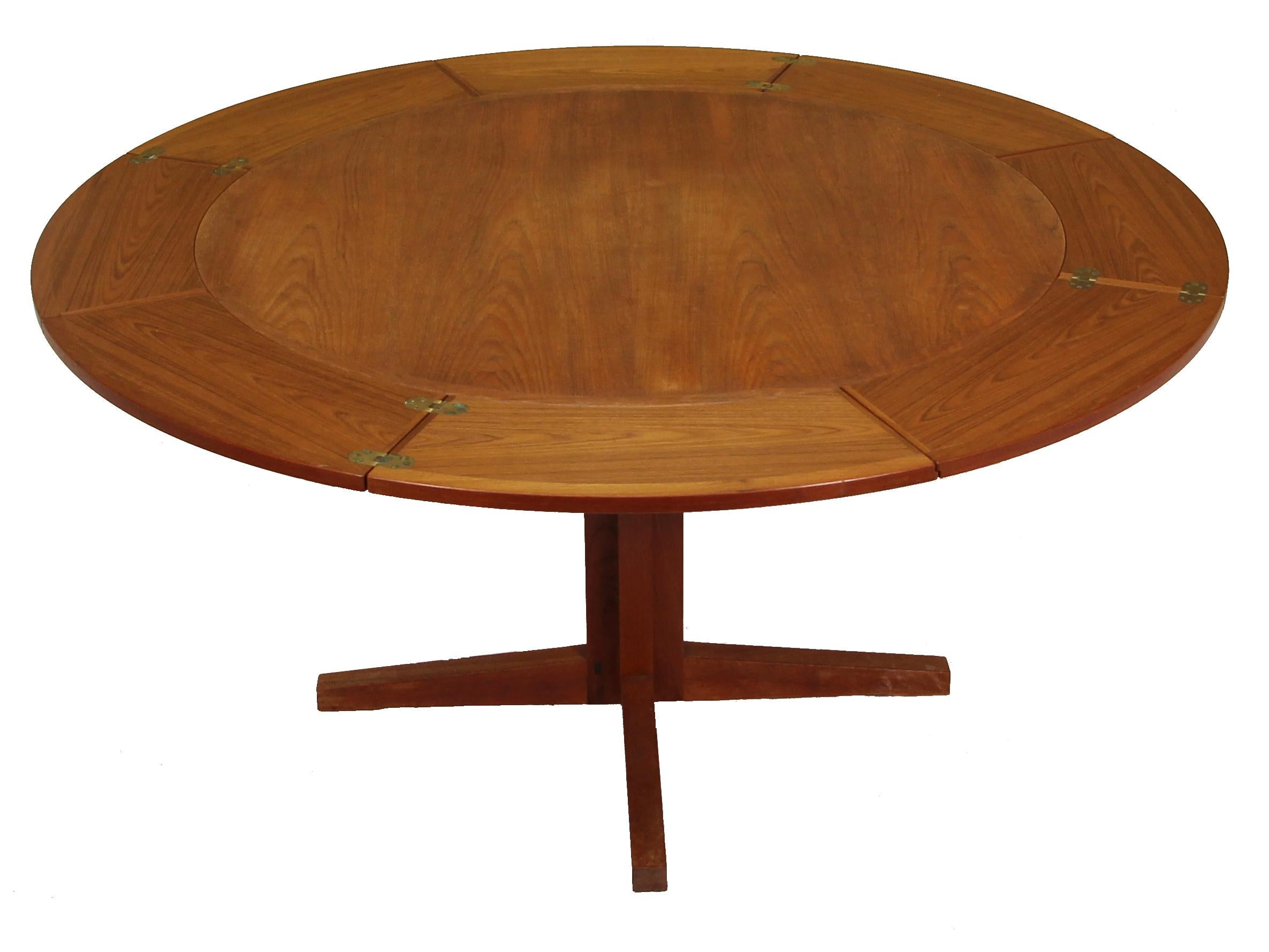 Very unique Lotus or flip flap dining table made by Dyrlund in Denmark in the 1960s. 
The table has a unique design. It has a pedestal base. It extends by unfolding four small leaves that are hidden underneath the center. Hence the name Lotus or