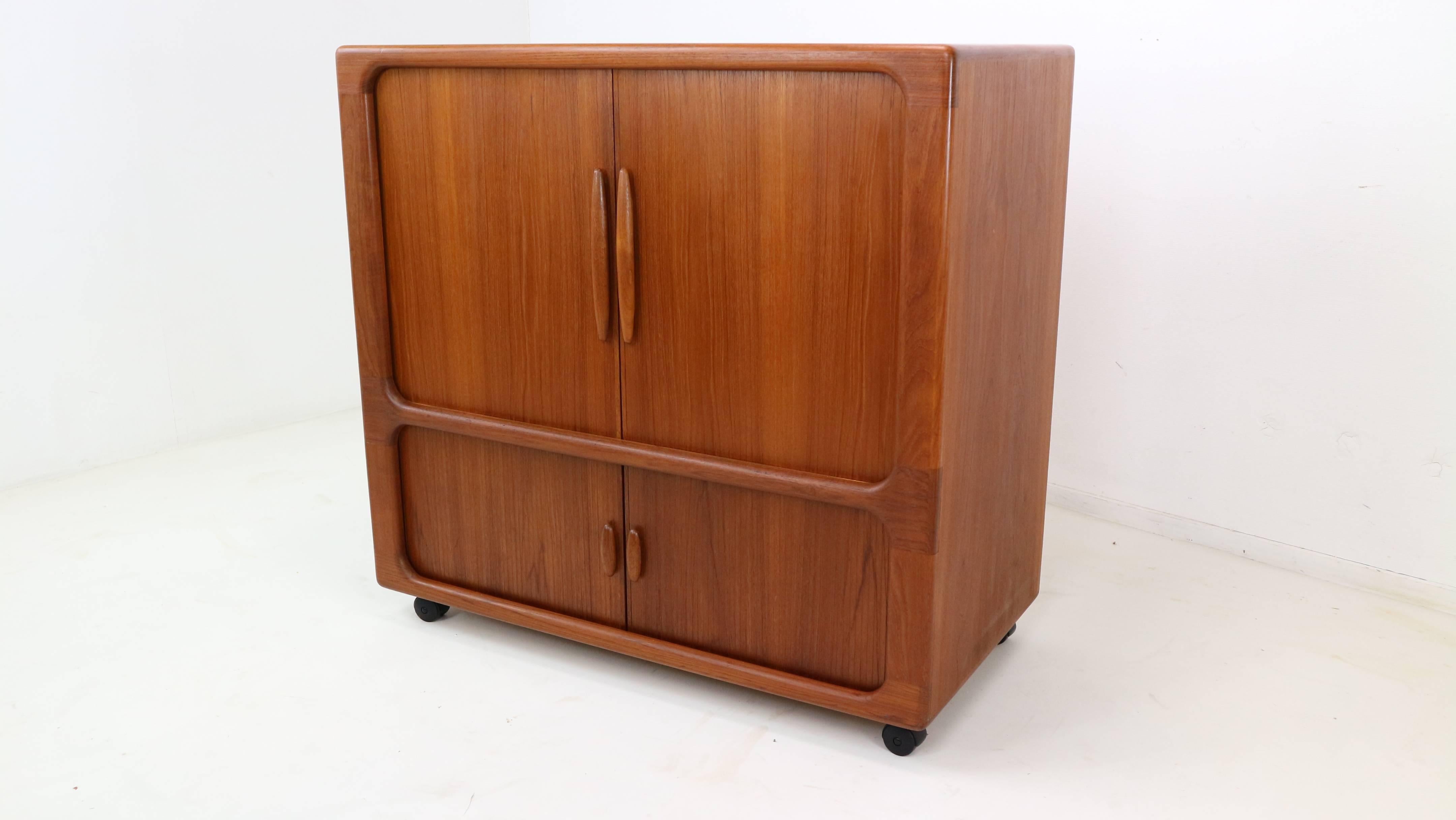 Dyrlund Tambour door Cabinet. 

A fabulous teak cabinet by high-end Danish furniture manufacturer Dyrlund. Features rounded edges
and two pairs of finely crafted tambour doors which slide back smoothly out of sight.
 
There is a large cupboard