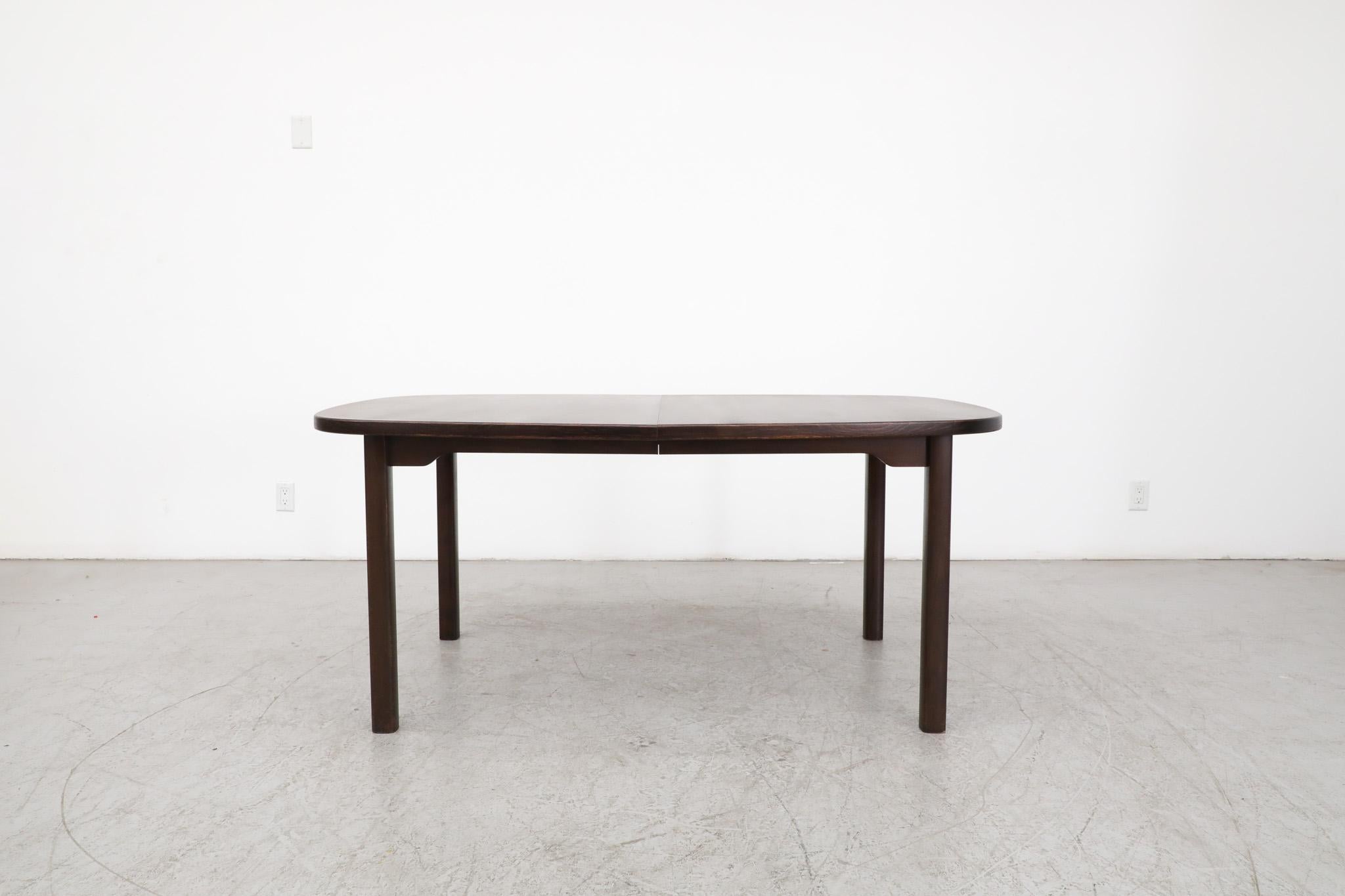 Mid-Century Dyrlund dark stained dining table with double extension leaves and round legs. Versatile dining table that fits up to 8 people (102.25