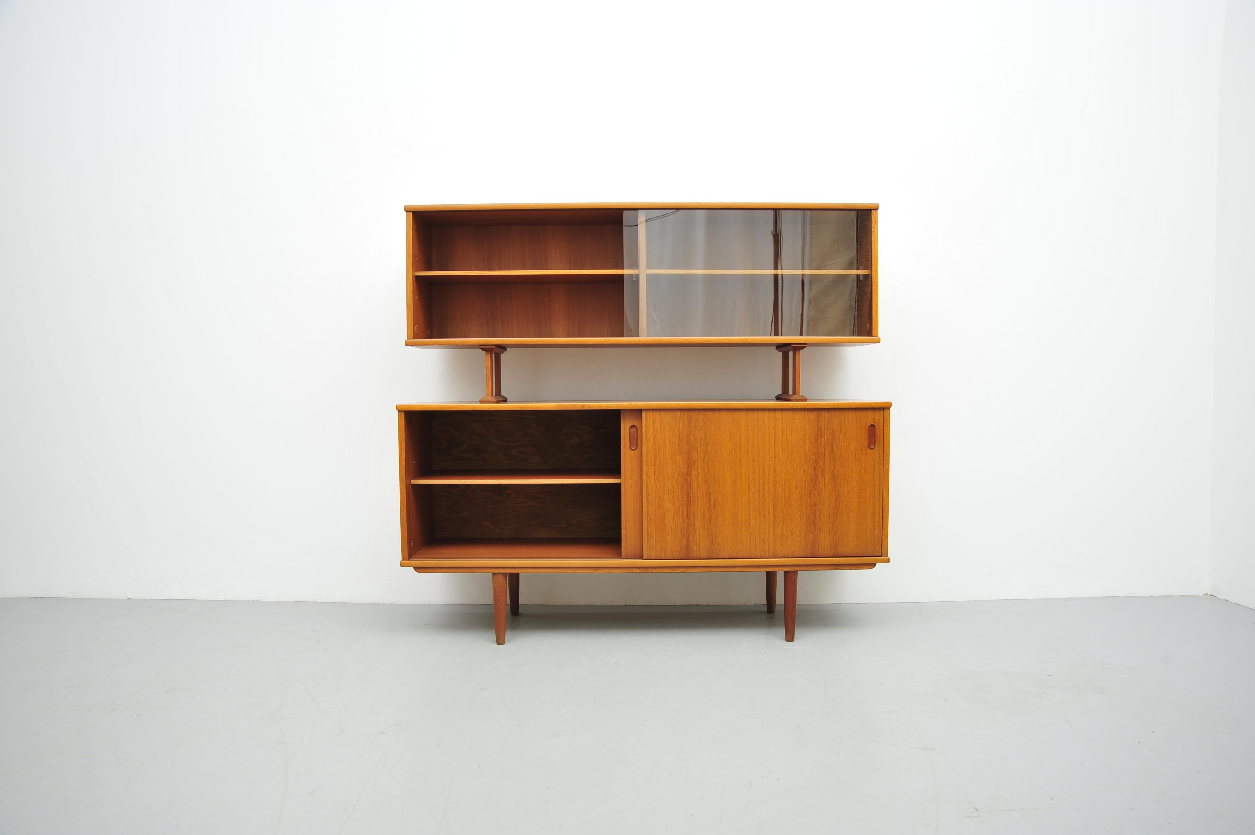 Dieses elegante Dyrlund Sideboard mit Aufsatz ist ein klassisches Beispiel für hochwertiges dänisches Design. Gefertigt aus Teakholz, bietet es eine großzügige Ablagefläche und Stauraum. Der Aufsatz verfügt über offene Regale sowie einen Bereich mit