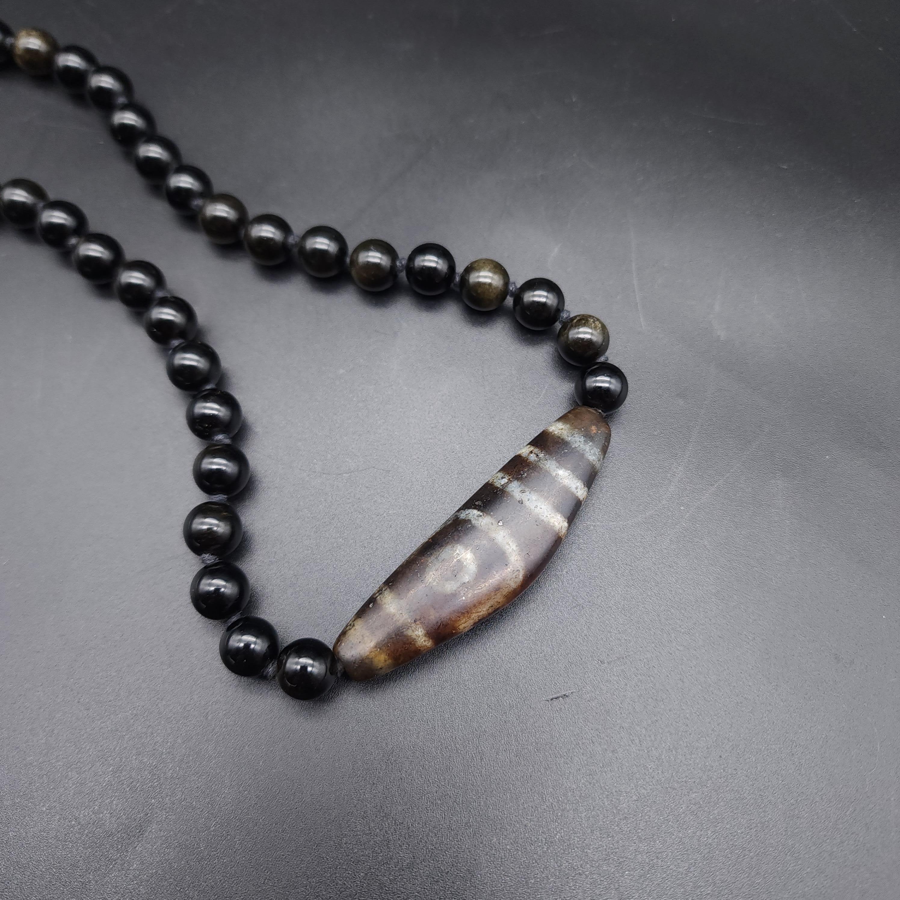 Necklace length: 48 cm / 18.5 in
Beads approx 1cm each, polished obsidian glass
Dzi pendant: 6.5 cm / 2.5 in wide
Marks / Hallmarks: 925 on clasp

Elevate your style with our stunning dzi centerpiece necklace, featuring mesmerizing obsidian beads