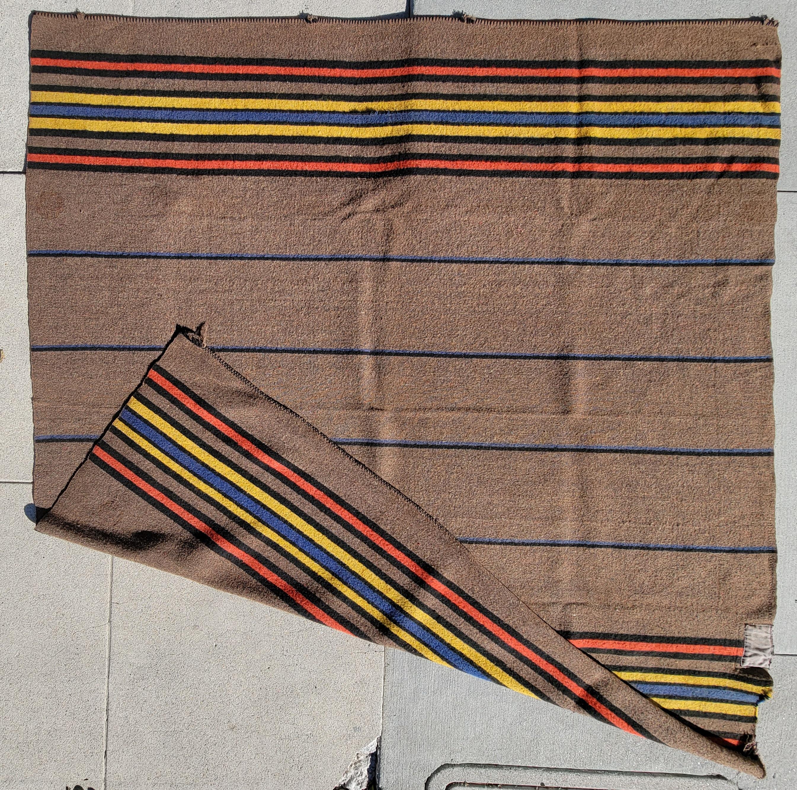 Striped all wool blanket with majority brown background, thin striped colorful accents provide a small touch of variety. There are some areas of wear to the edges. There is a patch on one side. This blanket is usable and very sturdy.