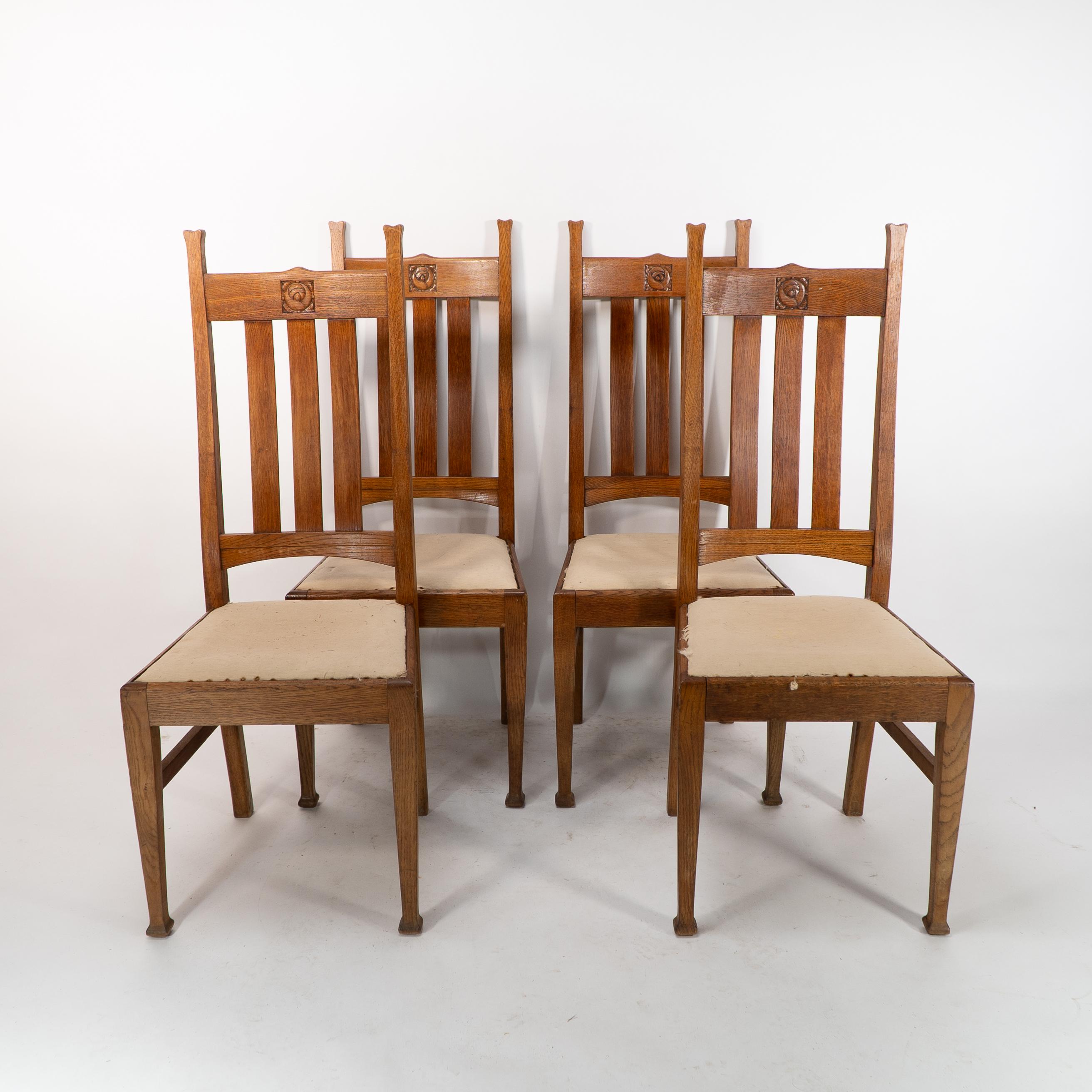 E A Taylor for Wylie and Lochhead Glasgow. A Set of four Arts and Crafts oak dining chairs with carved floral decoration to the head rests and a shaped comfortable back, drop in seats, high stretchers, standing on square tapering legs. Price for the