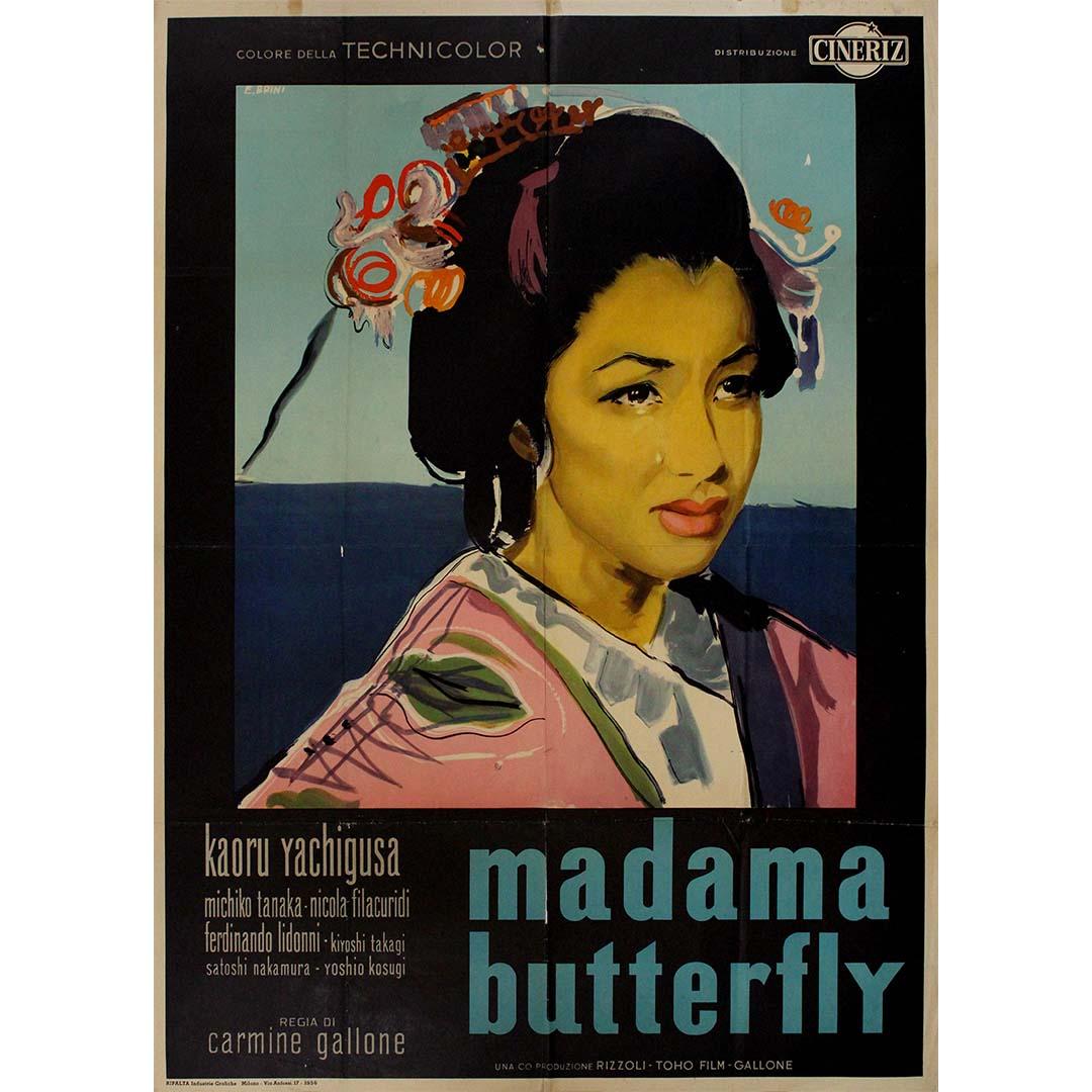 This elegant 1956 Italian film poster by E. Brini captures the poignant beauty and emotional depth of Madama Butterfly, a cinematic adaptation of Giacomo Puccini’s beloved opera. Painted in bold strokes yet soft tones, the image of a serene yet
