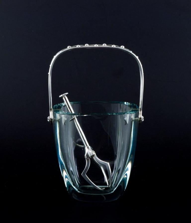 E. Dragsted, Danish silversmith.
Danish design. Modernist ice bucket in art glass with a sterling silver handle and a silver-plated metal ice tong.
Sleek Danish design.
From the 1960s/70s.
In perfect condition.
Handle stamped ED and