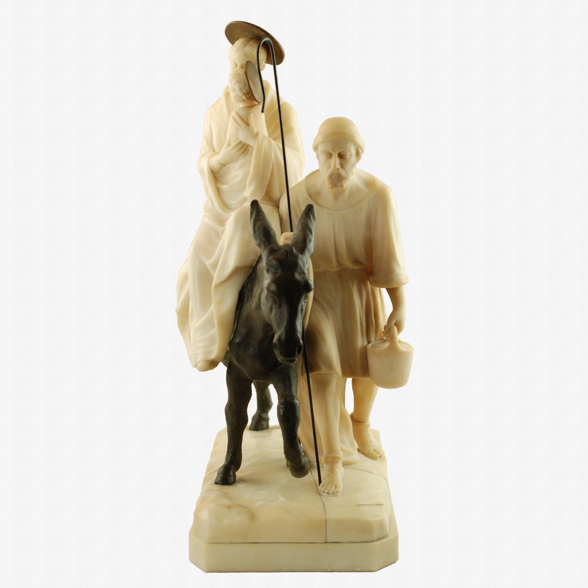 Ce groupe de figures en albâtre, bronze et marbre a été créé par le célèbre sculpteur italien Emilio P. Fiaschi (1858 - 1941).  La sculpture représente la fuite en Égypte de la Sainte Famille et a été réalisée avec le talent et la sensibilité