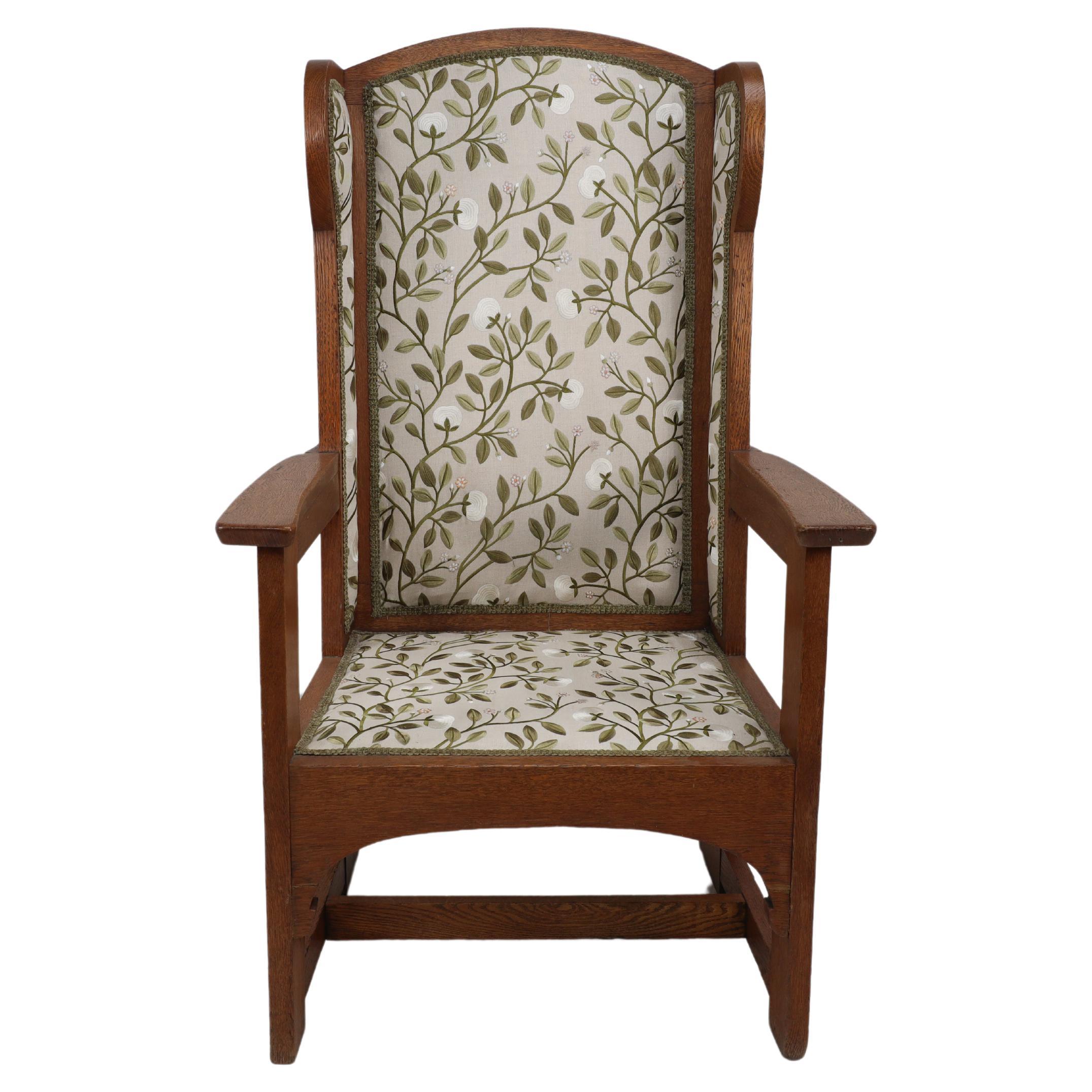 E G Punnet attributed. Probably made by William Birch and retailed by Goodyers of Regent Street. An Arts and Crafts oak wing back hall armchair using flat sided construction. With flowing arched aprons below the seat. Professionally re upholstered.