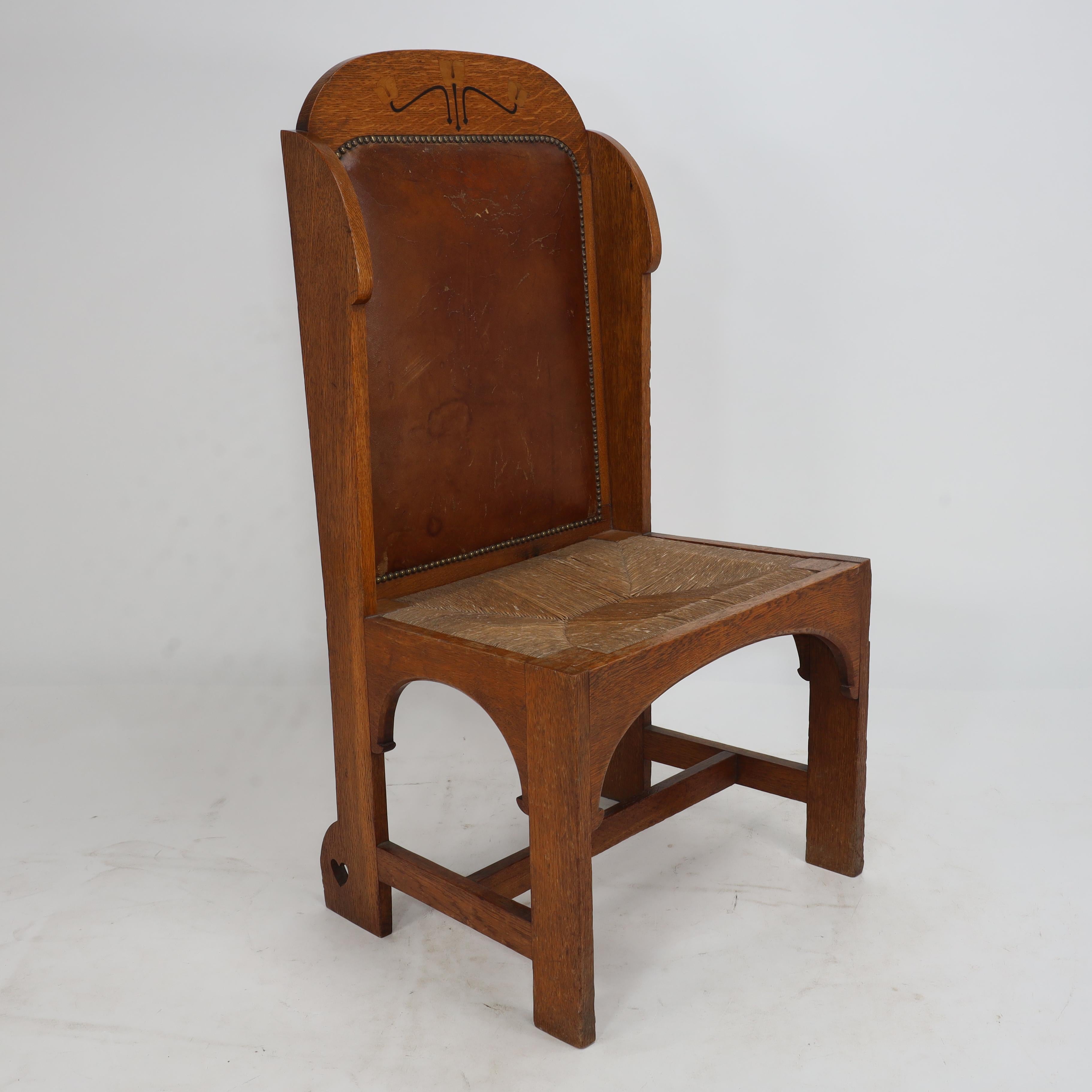 E G Punnet attributed. Probably made by William Birch and retailed by Goodyers of Regent Street. An Arts and Crafts oak wing back hall chair using flat sided construction. The head rest inlaid with sycamore tulips on ebonised stems ending with tiny
