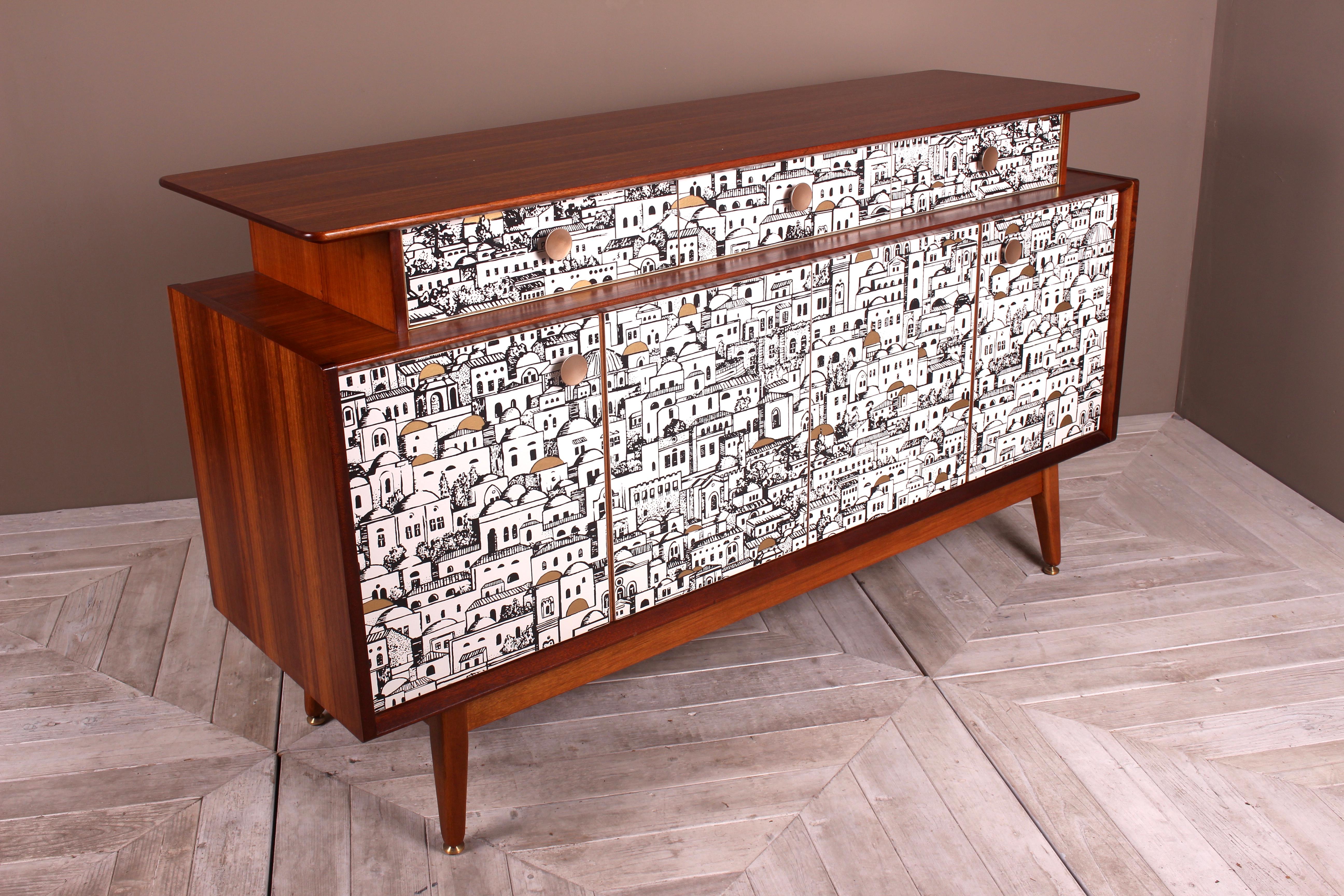 A beautifully made teak sideboard from 1958. Creatively decoupaged with a paper that featured in Piero Fornasetti’s Milan residence. The sideboard has been restored. Sanded and oiled by hand. A wonderfully figured top section holding three drawers