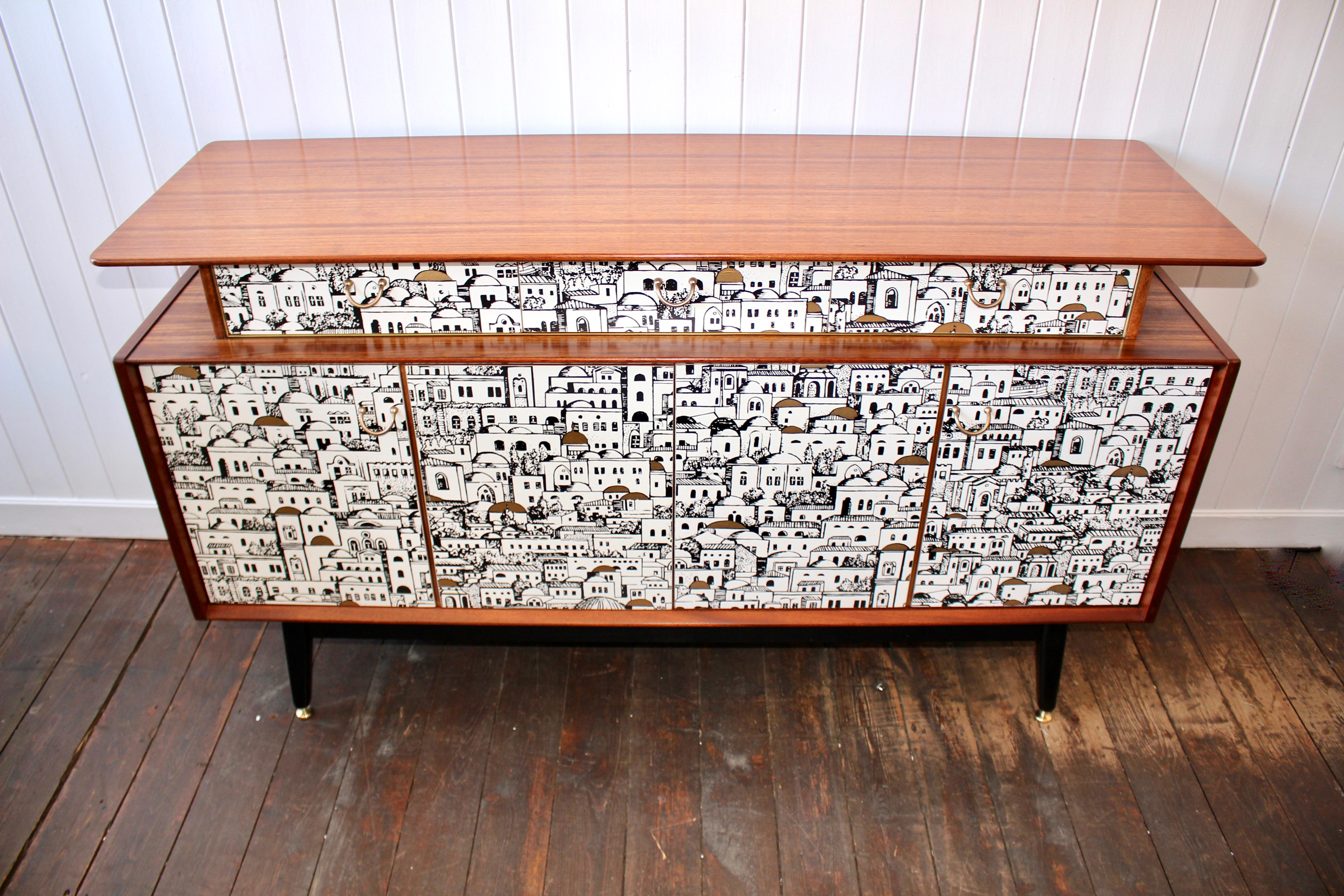 A beautifully made teak sideboard from 1958. Creatively decoupaged with a paper that featured in Piero Fornasetti’s Milan residence. The sideboard has been restored. Sanded and oiled by hand. A wonderfully figured top section holding three drawers