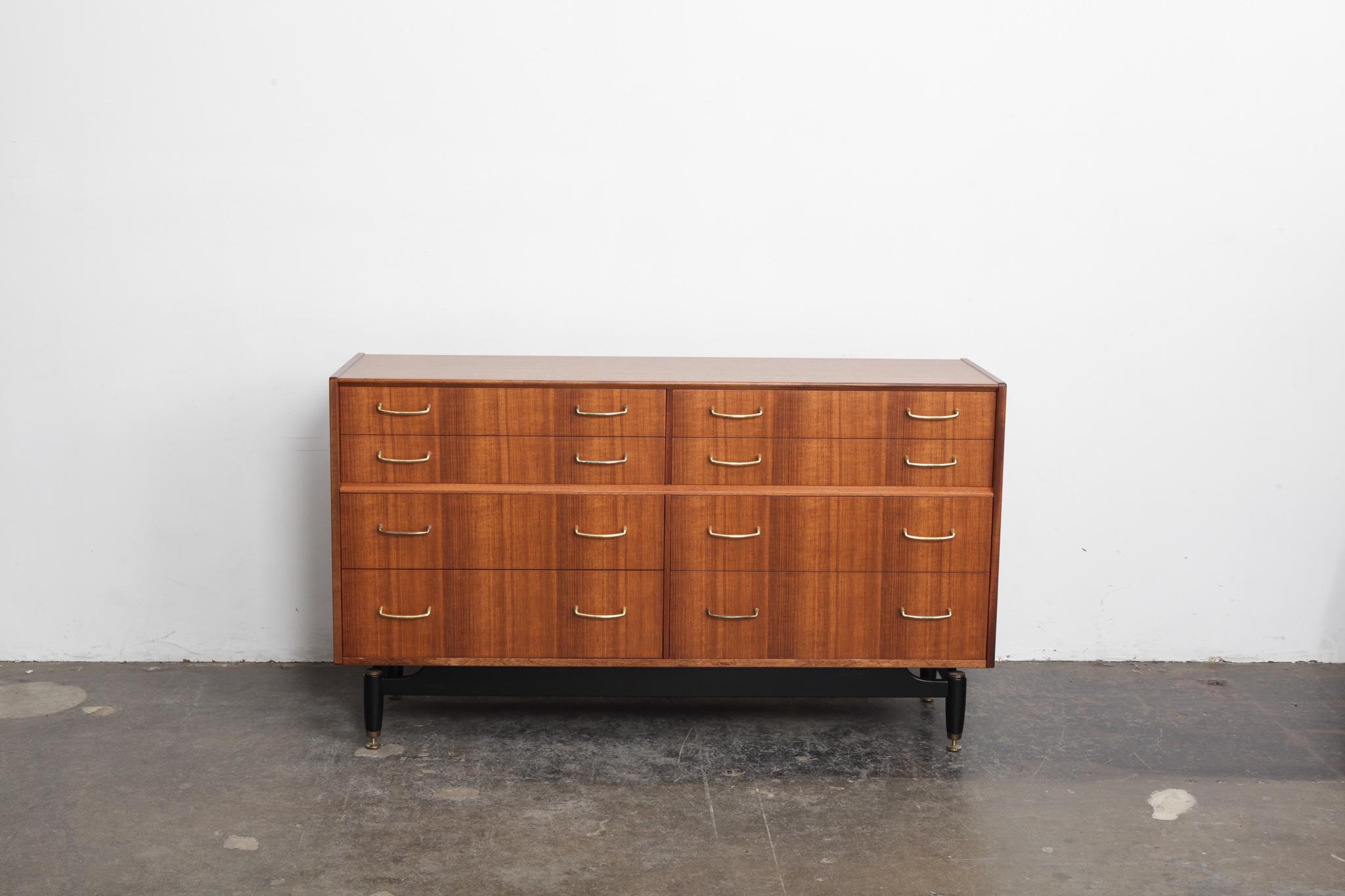 G Plan Tola wood long 8-drawer dresser with brass metal pulls, ebonized base with brass feet and newly refinished in lacquer. Beautiful grain throughout, this dresser is part of the 